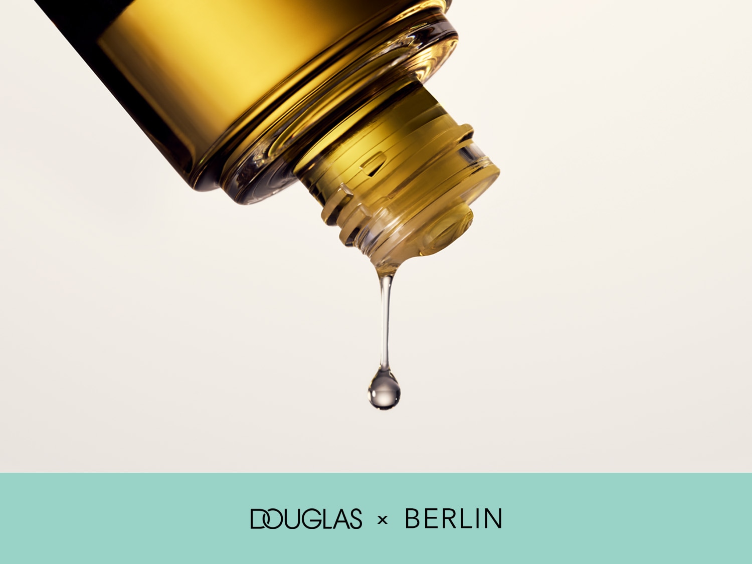 Nahaufnahme einer goldenen Flasche, aus der ein Tropfen Öl austritt, mit dem Schriftzug Douglas x Berlin.