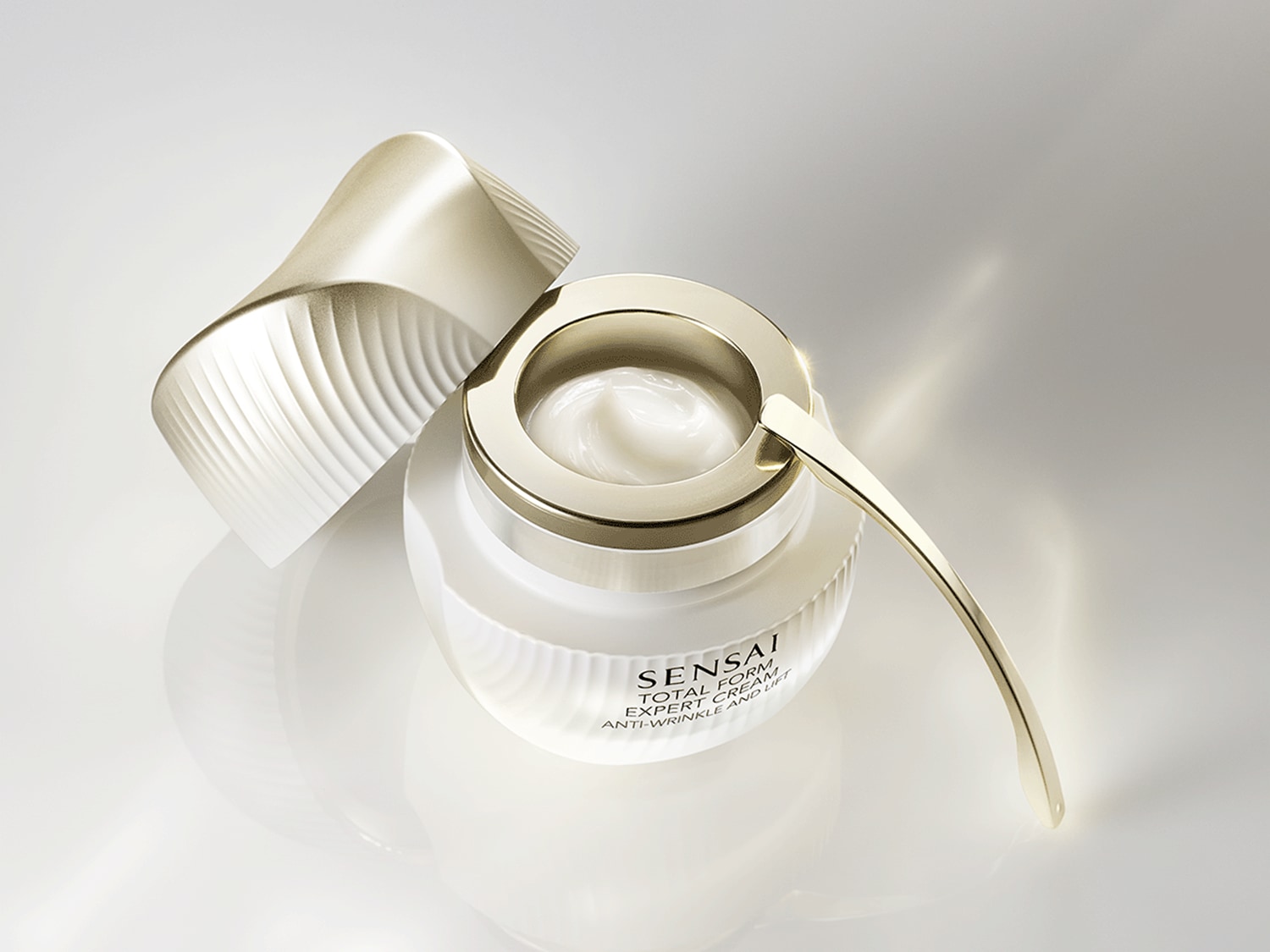 Krem Sensai Total Form Expert Cream Anti-Wrinkle and Lift w białym słoiczku ze złotymi akcentami i otwartym wieczkiem ukazuje swoją bogatą, kremową konsystencję.