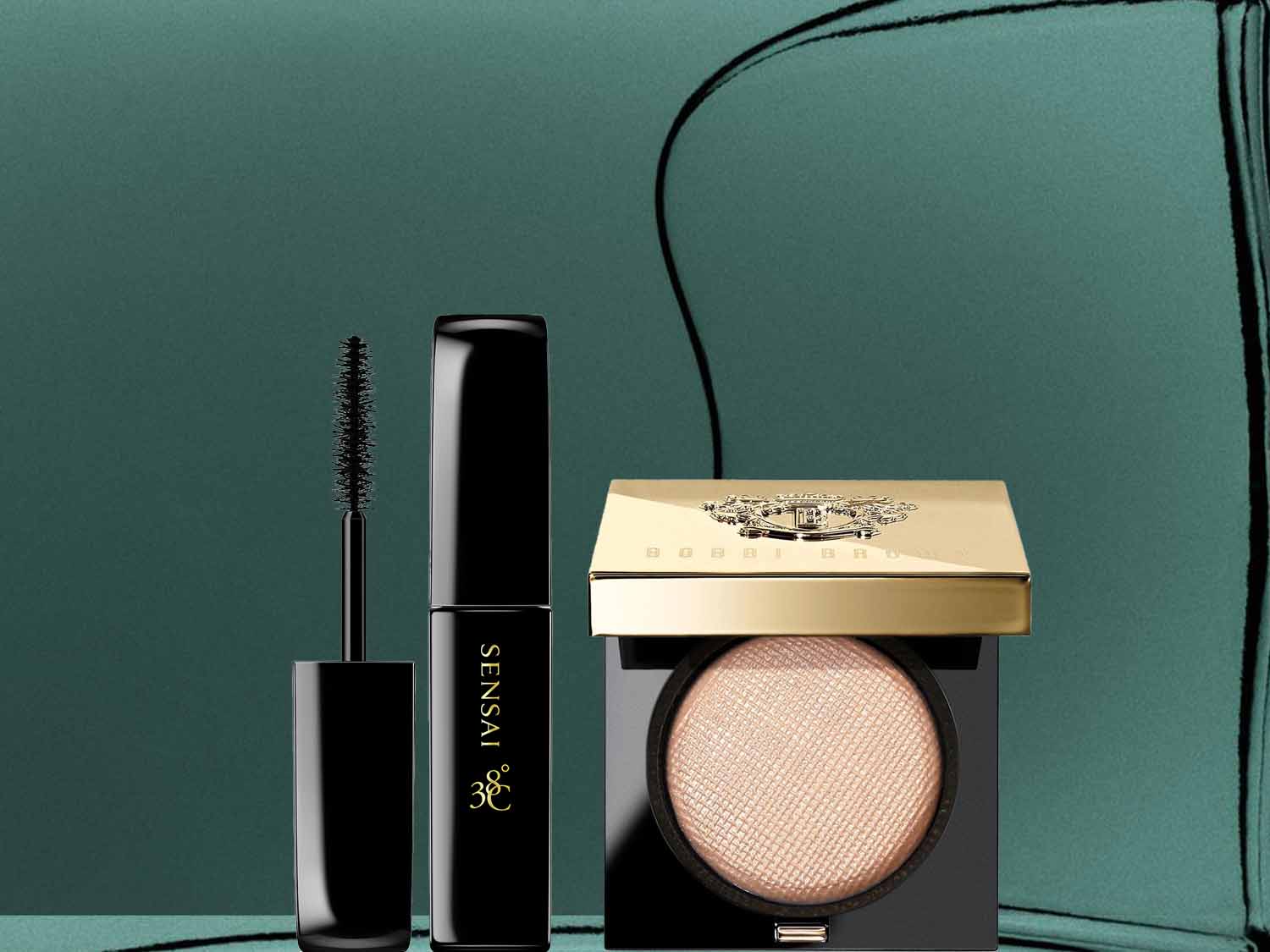 Na ciemnozielonym tle znajdują się tusz do rzęs Sensai w czarnym opakowaniu i rozświetlacz Bobbi Brown w czarno-złotym opakowaniu.