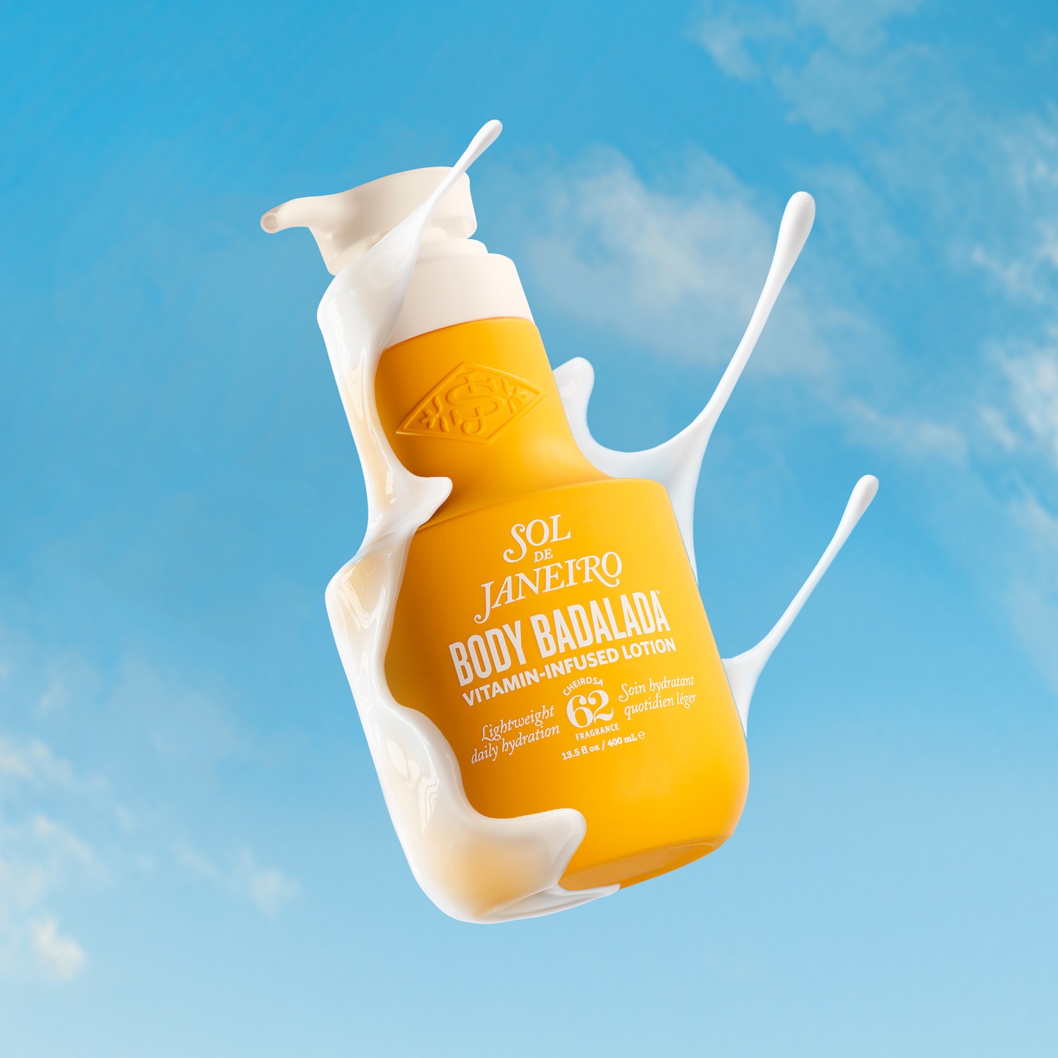 Badalada Vitamin-Infused Lotion von Sol de Janeiro in einer gelben Falsche mit weißer Pumpe und spritzender Lotion vor blauem Himmel.