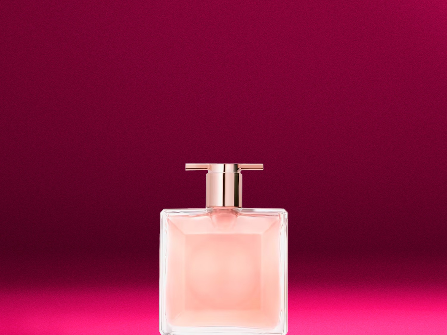 Ein rechteckiger, transparenter Parfümflakon mit rosafarbenem Inhalt und goldenem Verschluss steht vor einem leuchtend pinkfarbenen Hintergrund.