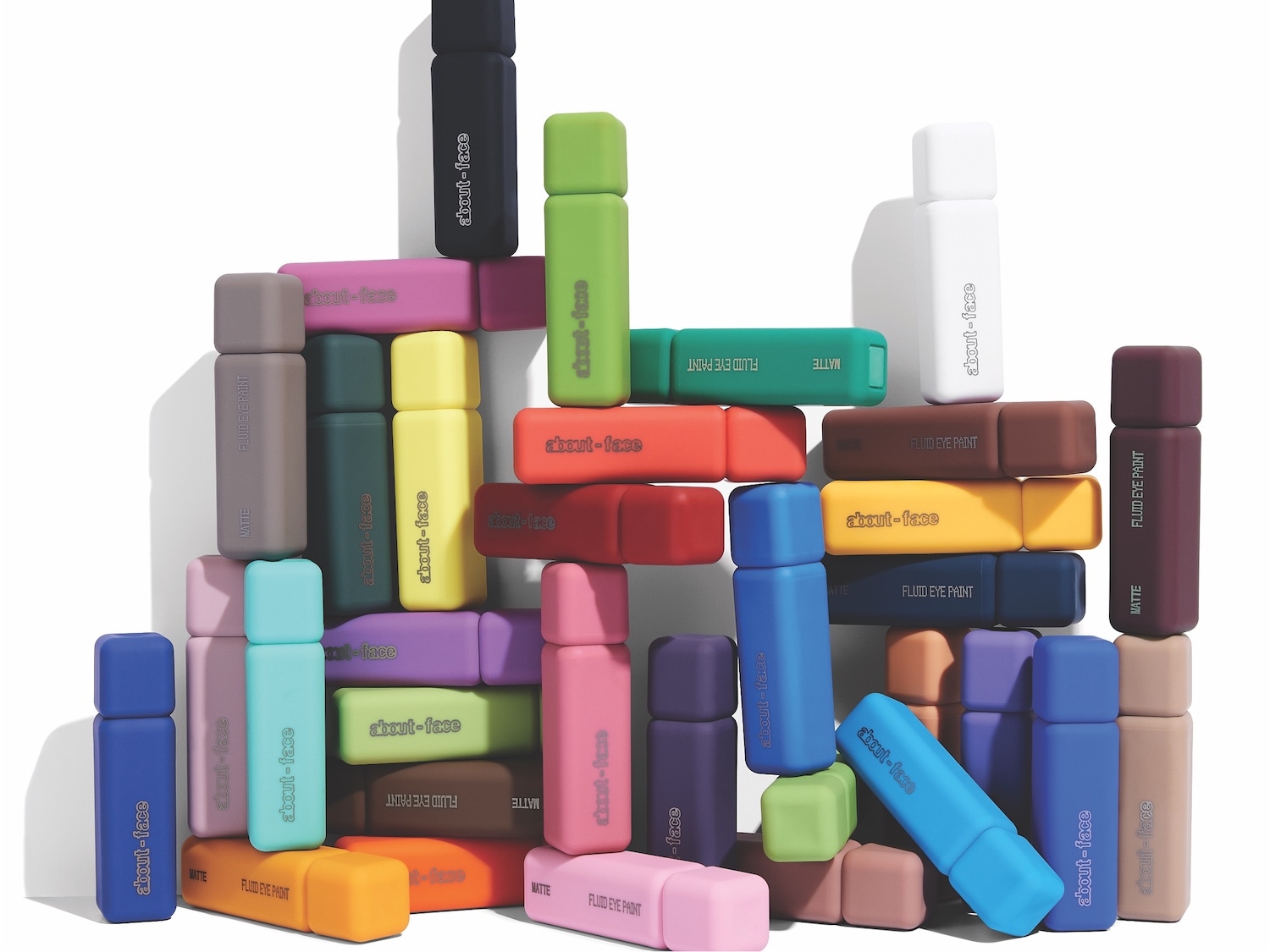 Eine vielzahl von About-Face Fluid Eye Paint in verschiedenen Farben, darunter Schwarz, Grün, Gelb, Orange, Blau, Lila, Rosa, Braun und Weiß, die in einer gestapelten Anordnung präsentiert werden.