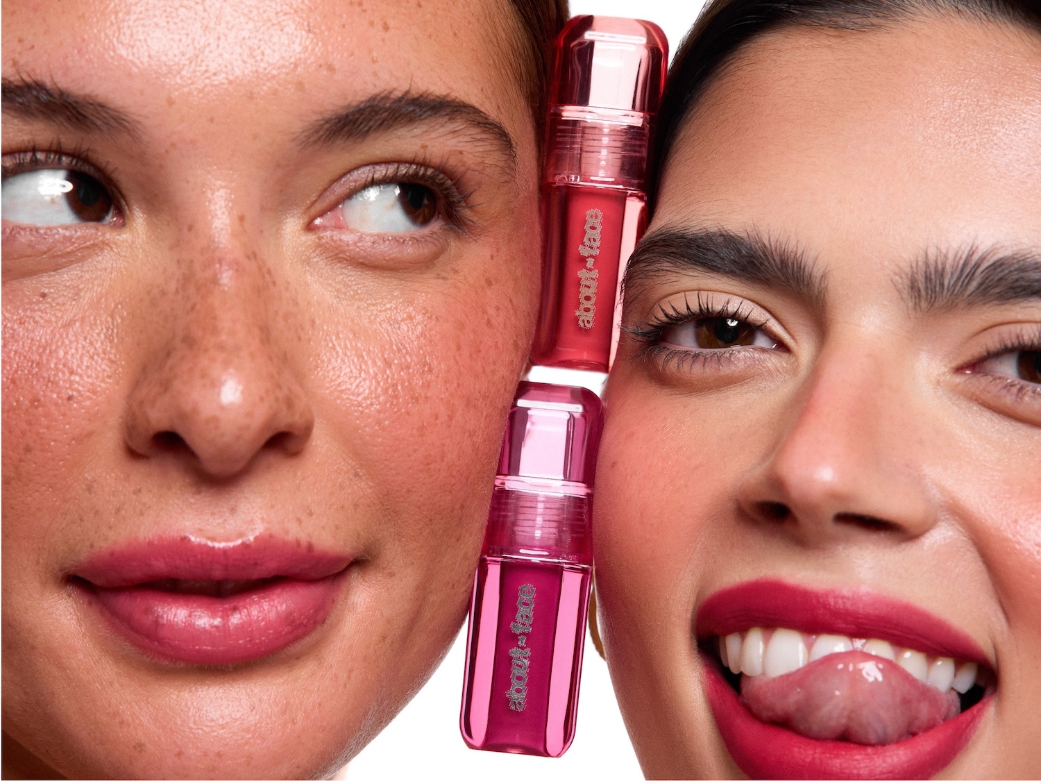Nahaufnahme von zwei Frauen mit rosa Lippenstift der Marke About-Face, der zwischen ihren Gesichtern gehalten wird.