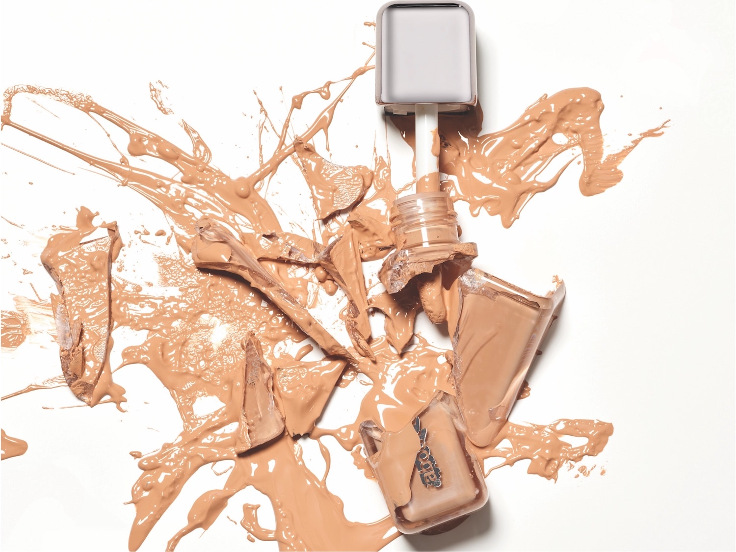 Nahaufnahme eines zerbrochenen Fundamentbehälters, der beigefarbene Flüssigkeit auf einer weißen Oberfläche verschüttet.