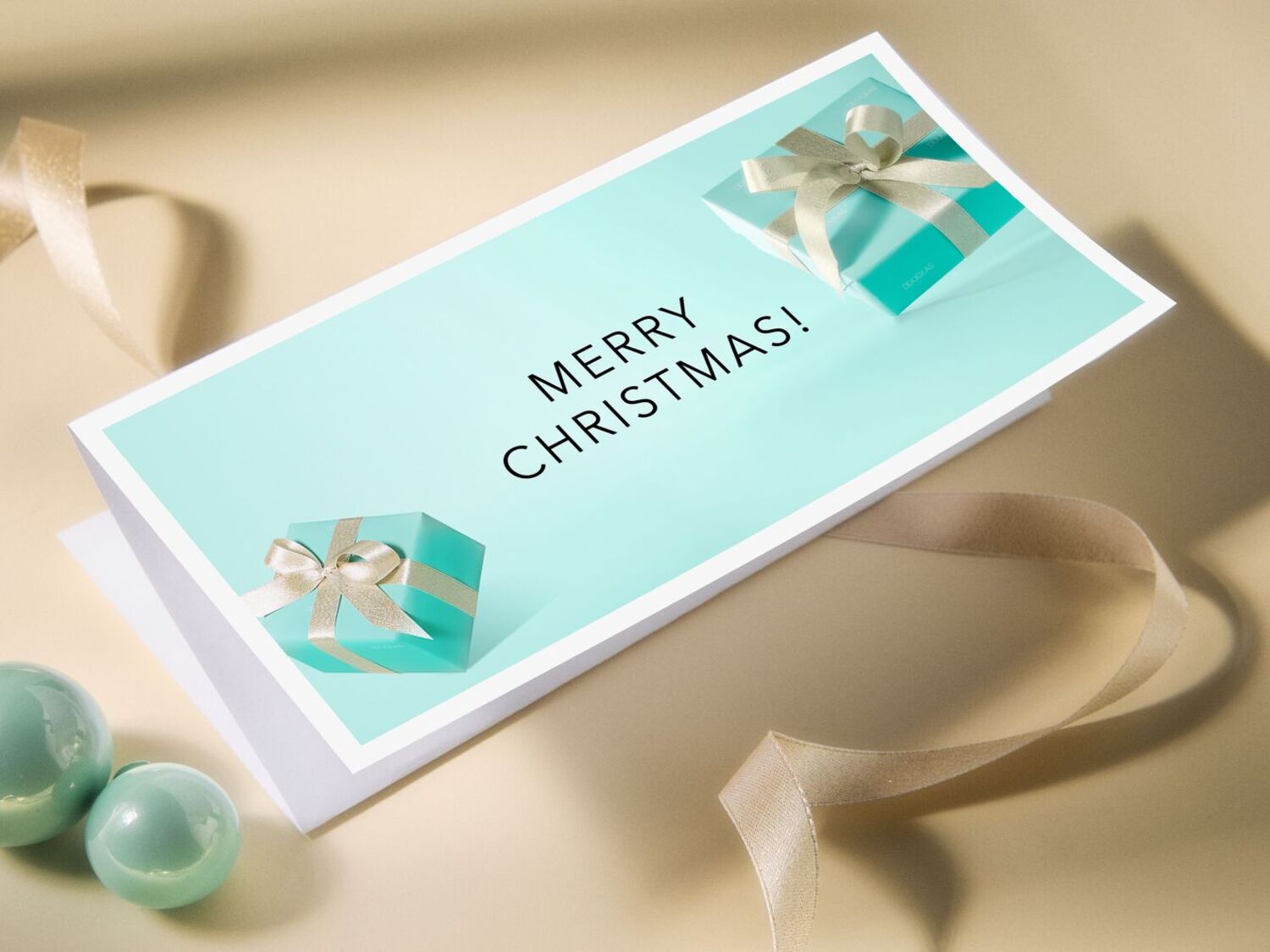 Carte de vœux avec le message « Joyeux Noël ! », ornée de deux boîtes turquoise décorées de rubans dorés, évoquant l'esprit festif des cadeaux.