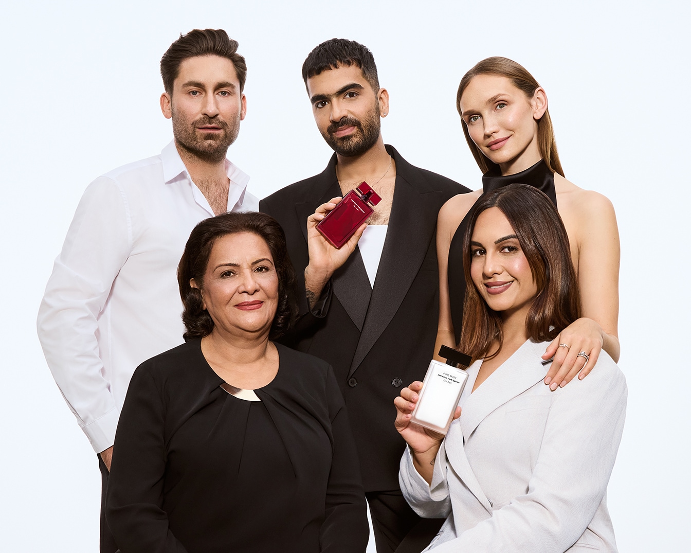 Das Bild zeigt Creator Arya Shirazi zusammen mit seiner Familie und engen Freunden vor einem weißen Hintergrund. Im Vordergrund sitzen Aryas Mutter und Schwester; die Schwester hält den Duft for her PURE MUSC in der Hand. Dahinter stehen drei Personen: links Aryas Partner, in der Mitte Arya mit dem Duft for her eau de parfum intense und ganz rechts die beste Freundin Anna.