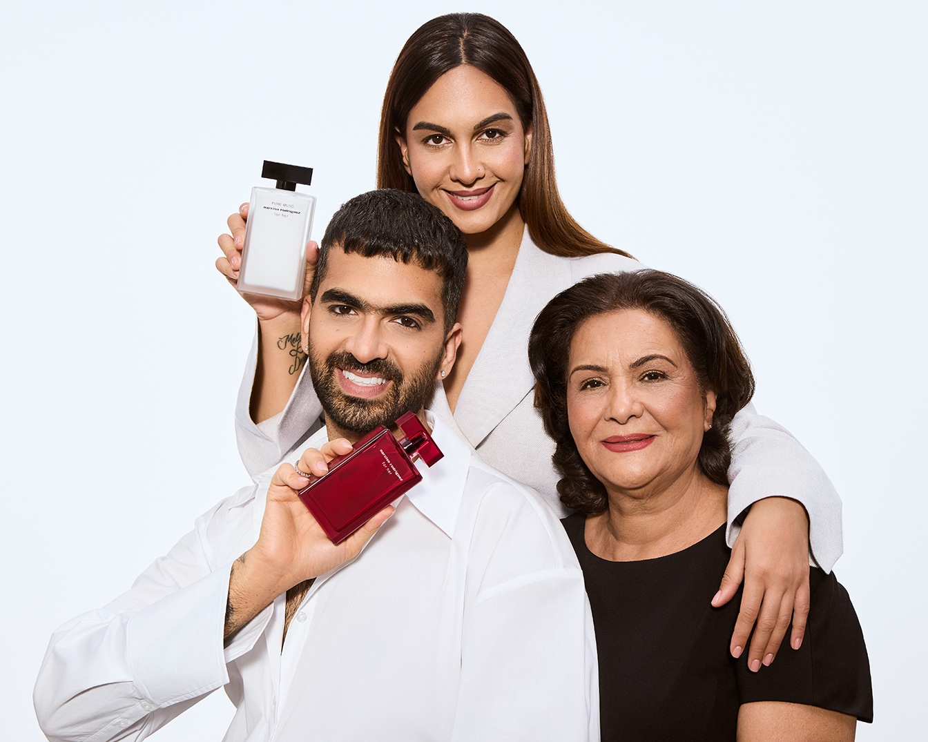 Arya hält den roten for her eau de parfum intense Duftflakon, während seine Schwester den weißen for her PURE MUSC Duftflakon von narciso rodriguez präsentiert, beide sind direkt neben ihrer Mutter.