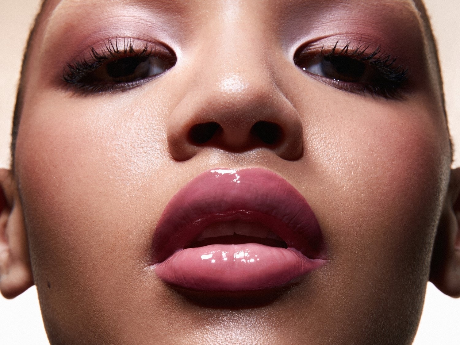 Gros plan sur un visage féminin avec un maquillage éclatant : fard à paupières rose et lèvres brillantes, mettant en valeur un look beauté frais et moderne.