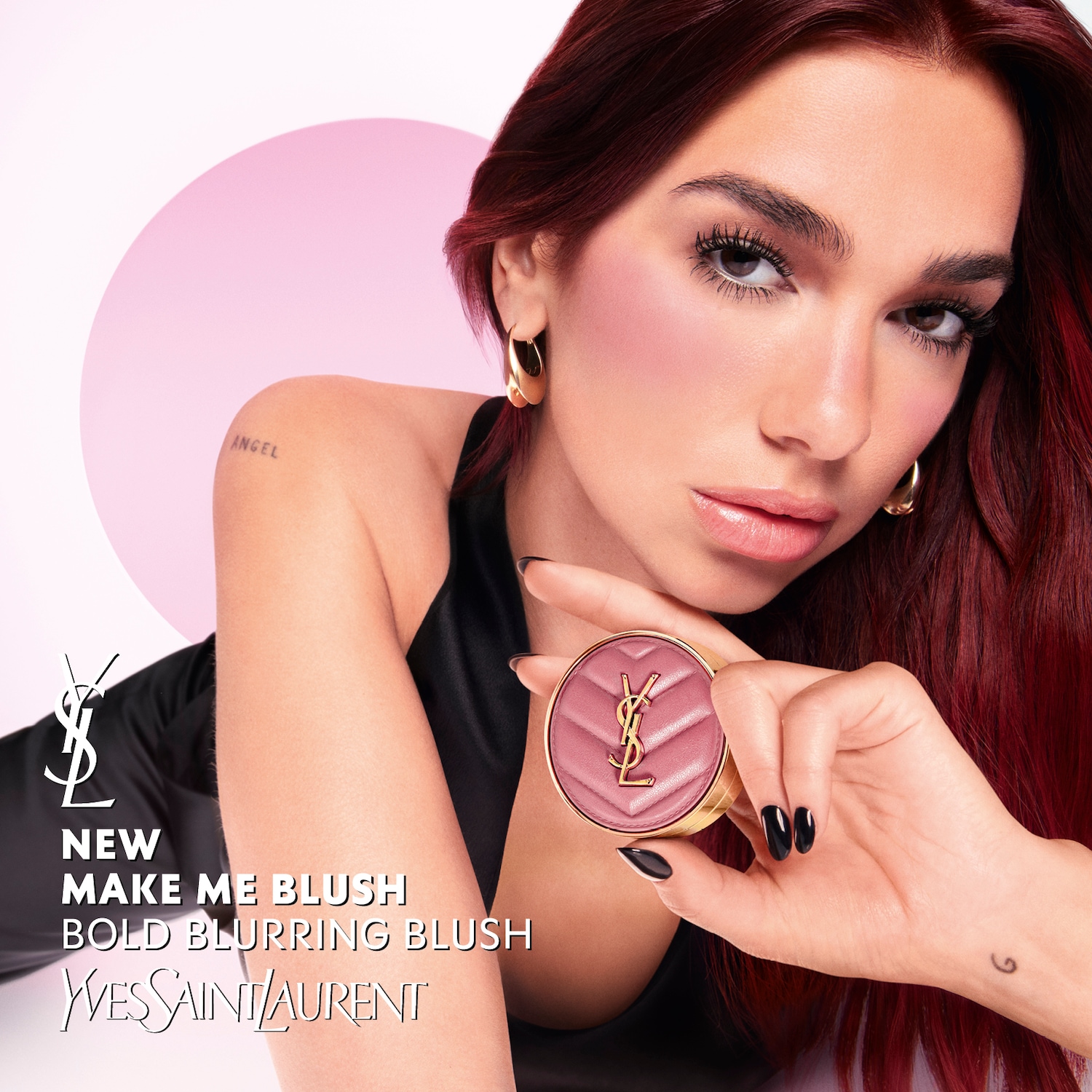 Kobieta z rudymi włosami prezentuje nowy róż do policzków Yves Saint Laurent „Make Me Blush” w puderniczce w kolorze różowym ze złotym logo YSL.