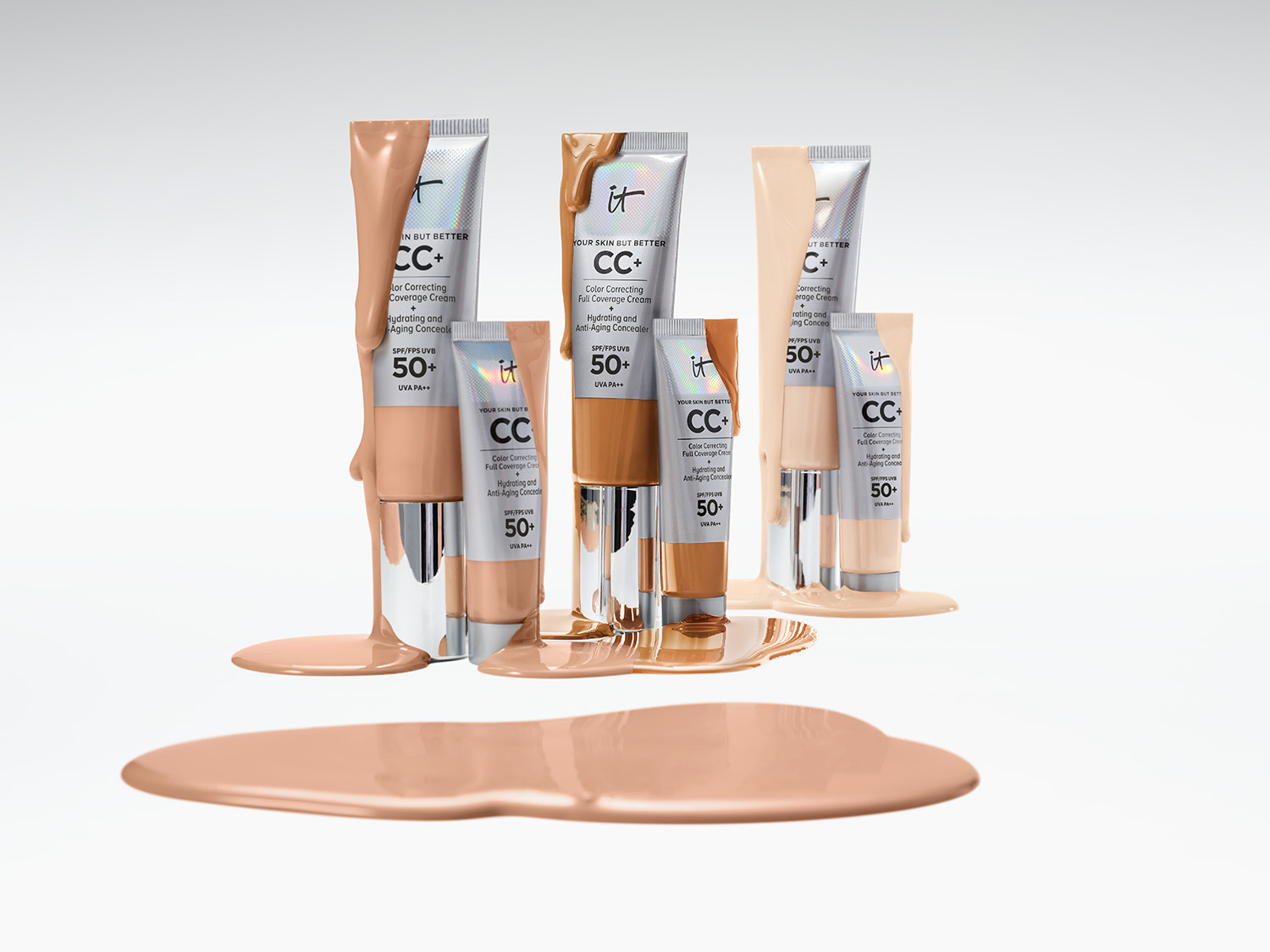 Różne odcienie kremu CC IT Cosmetics w srebrnych tubkach, z SPF 50+, rozlane na białym tle, tworząc efektowną kompozycję.