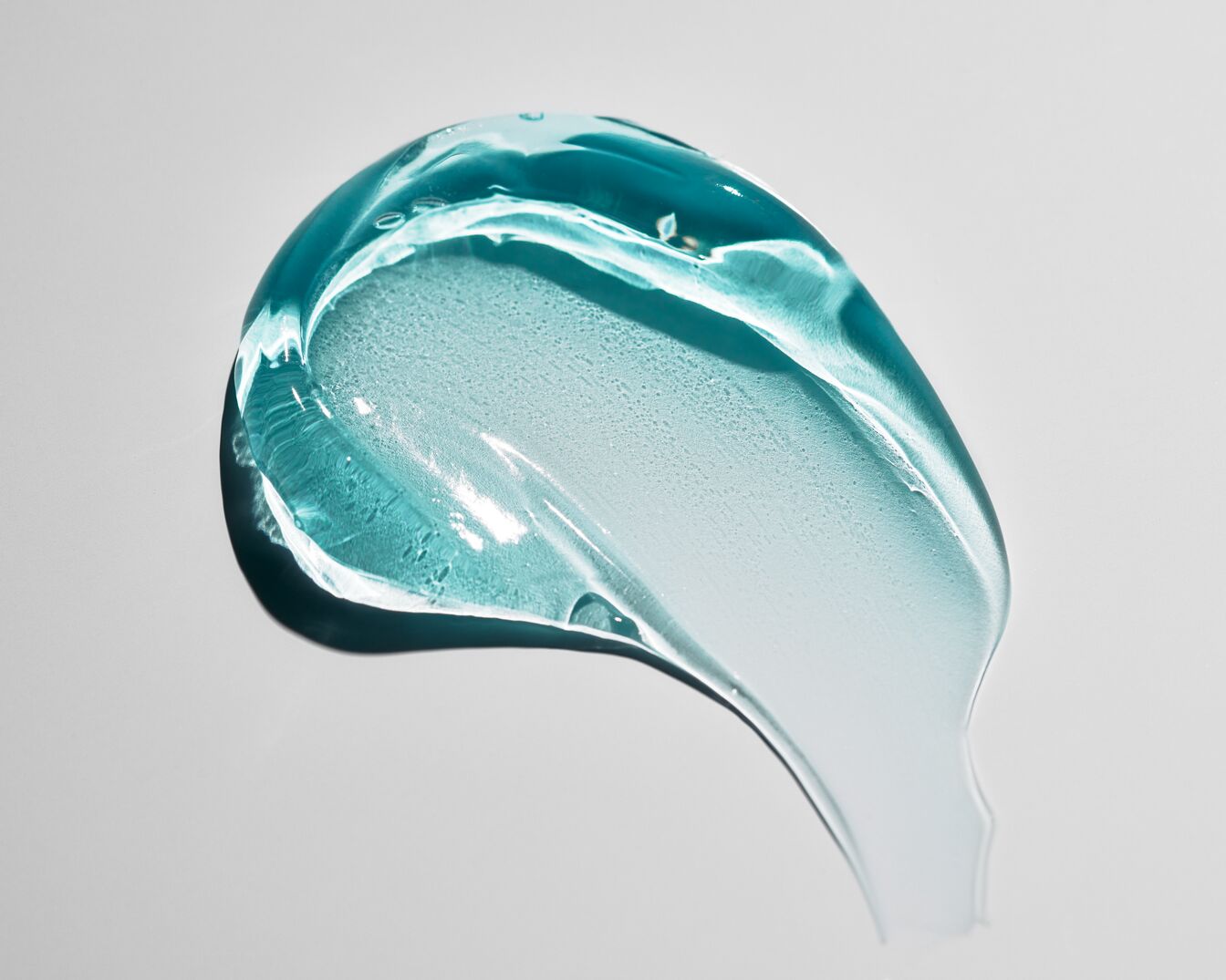 Nahaufnahme eines Klecks transparenten, hellblauen Gels, das eine glatte, leicht klebrige Textur zeigt.