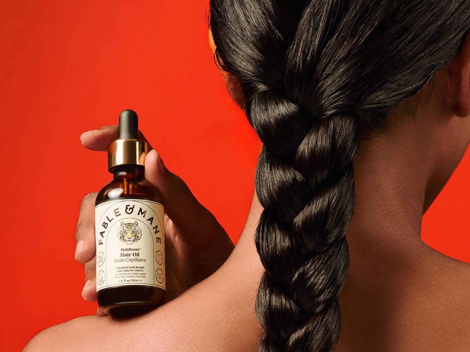 L'huile capillaire HoliRoots™ de Fable & Mane dans un flacon en verre brun avec un bouchon doré et une pipette noire, promettant des cheveux plus forts grâce à des racines saines.