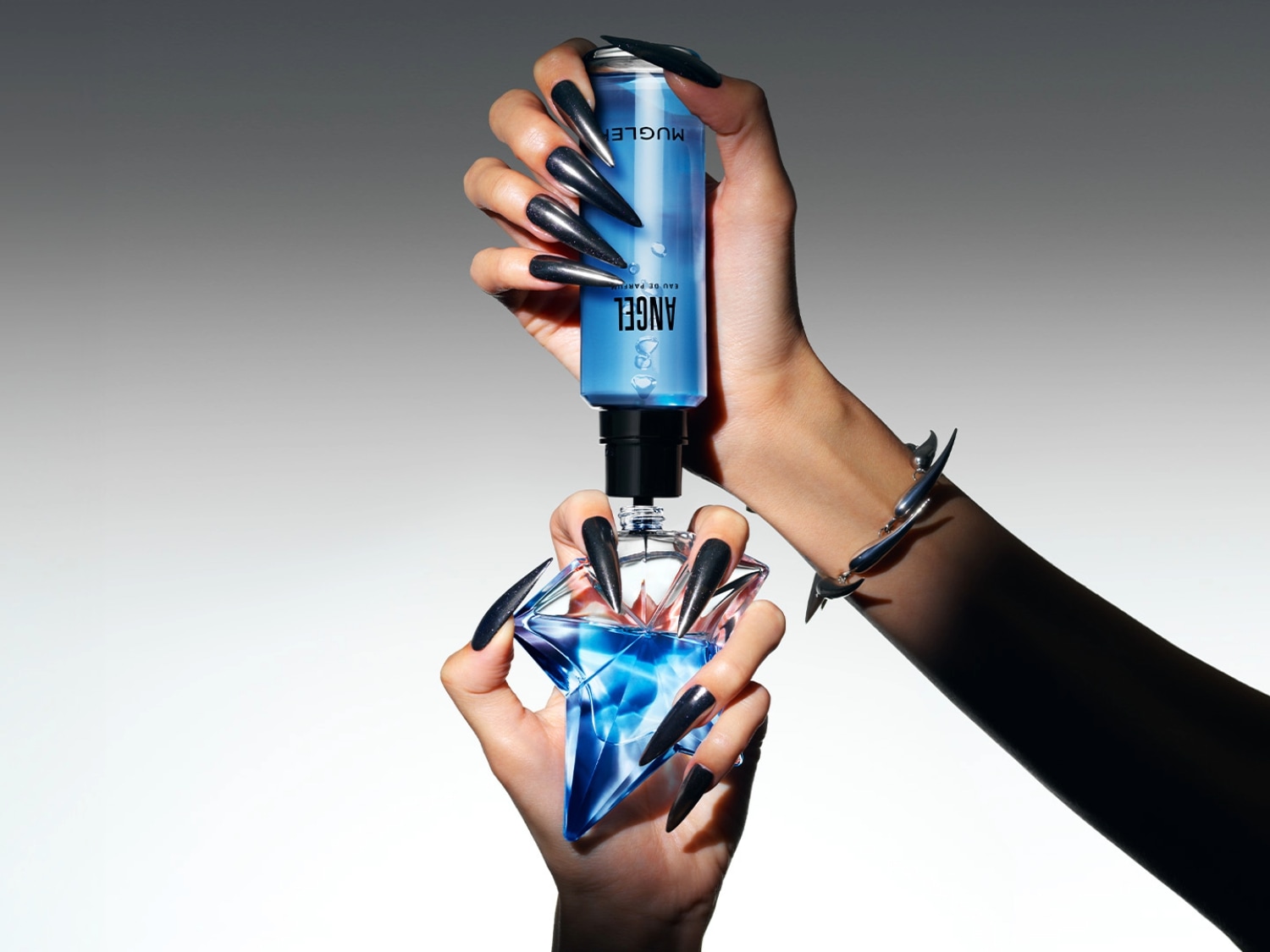 Die Hände mit langen, glänzend schwarzen Nägeln halten eine blaue Angel Eau de Parfum-Flasche und einen Nachfüllflakon.