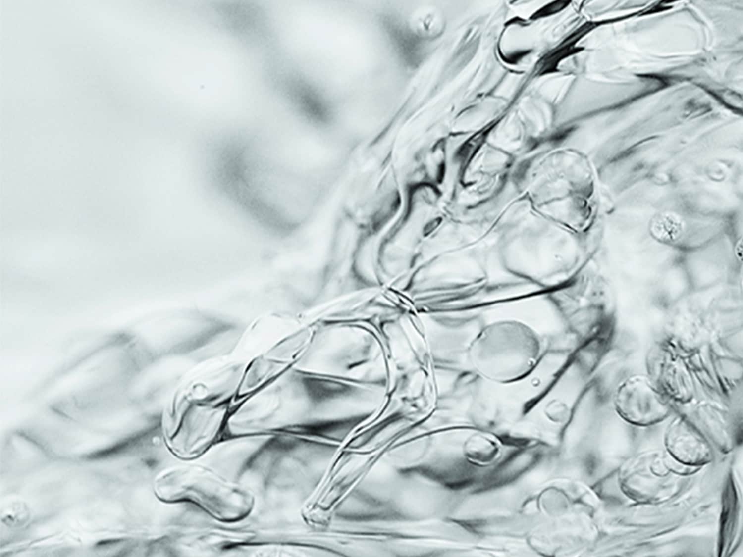 Primo piano di un liquido trasparente e denso con bolle, che suggerisce idratazione e purezza.