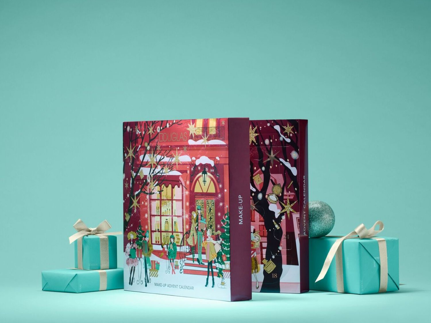Calendario dell'Avvento Make-Up Douglas con vetrina natalizia e persone disegnate sulla confezione, circondato da regali turchesi con fiocchi dorati.