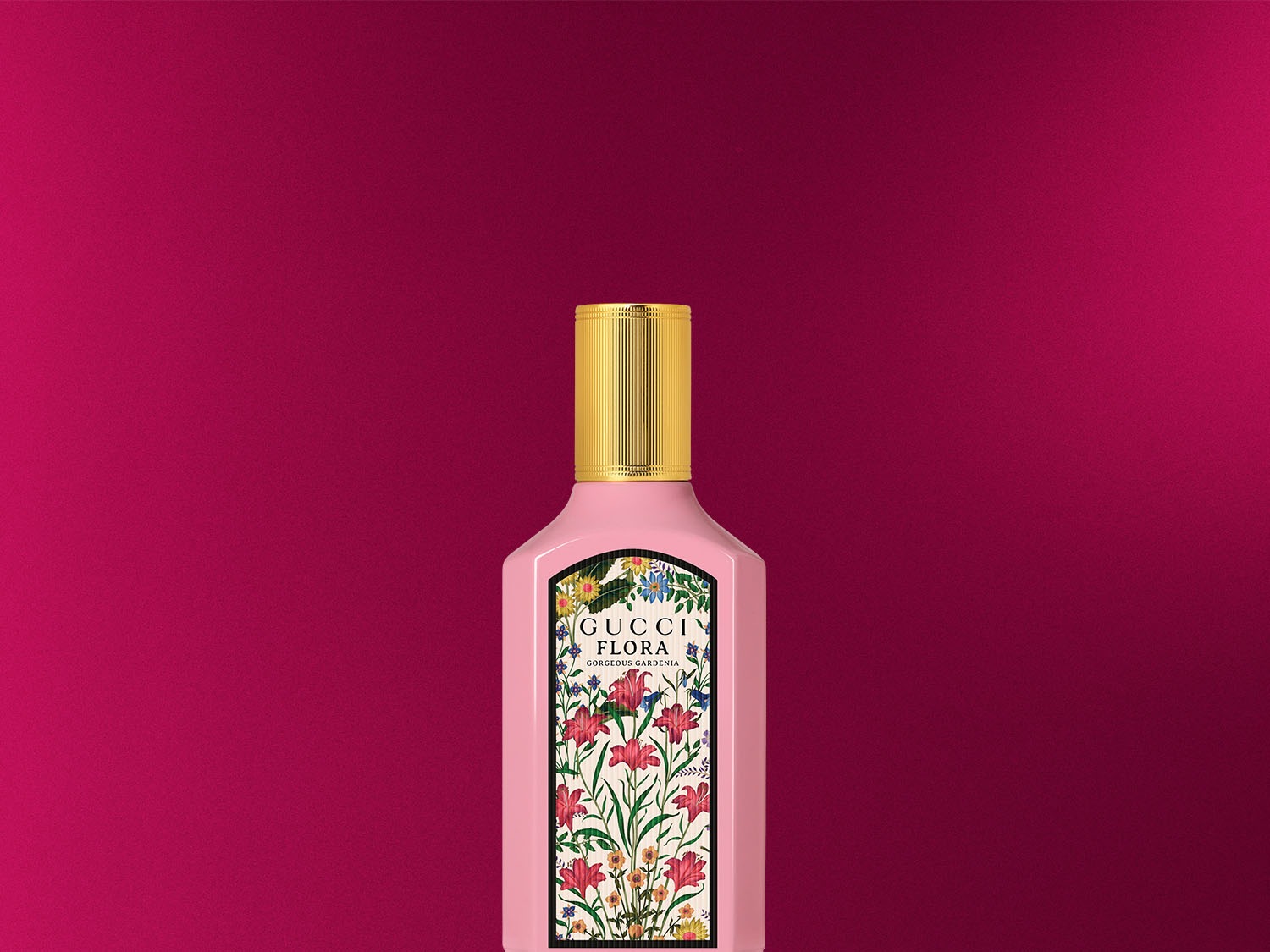 A Gucci Flora Gorgeous Gardenia rózsaszín üvegben, arany kupakkal, virágmintás címkével egy magenta háttér előtt.