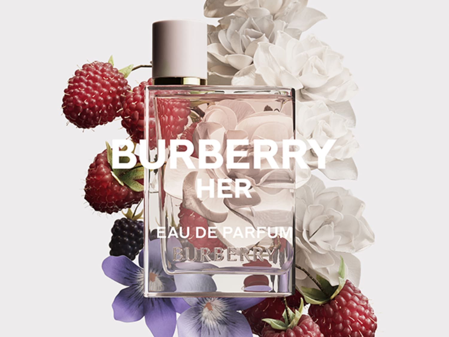 Descubre Burberry Her Eau de Parfum, una fragancia floral frutal con notas de bayas rojas, jazmín y almizcle, presentada en un elegante frasco adornado con flores y frambuesas.