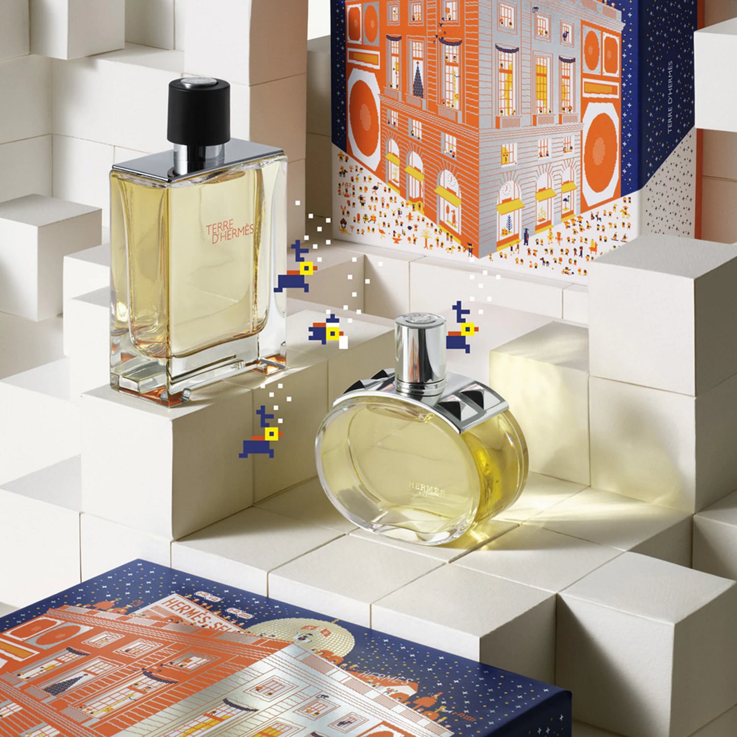 Découvrez Terre d'Hermès, un parfum boisé et élégant présenté dans un flacon rectangulaire et un flacon rond, posés sur des cubes blancs avec des motifs festifs sur les boîtes.