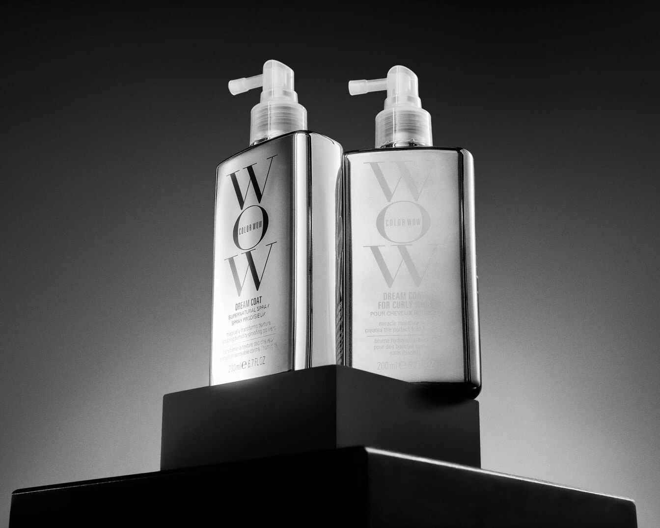 Ecco due flaconi di Color Wow Dream Coat, uno per capelli lisci e uno per capelli ricci, entrambi con erogatore spray trasparente, per trasformare magicamente la texture dei tuoi capelli.