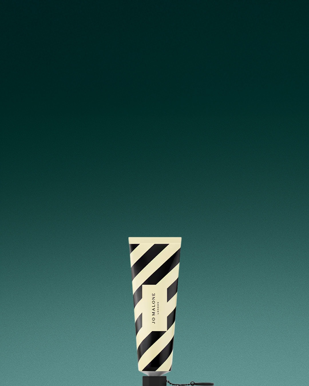 Krem do rąk Jo Malone London w tubce w biało-czarne paski na tle w kolorze morskim.