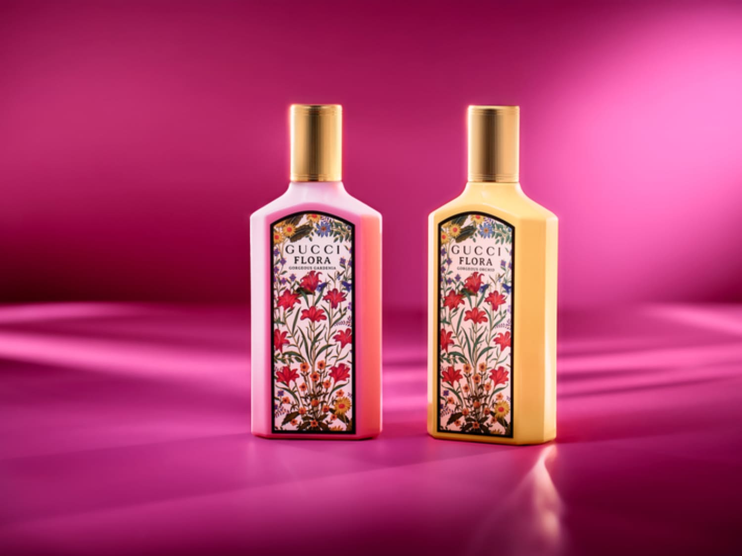 Zwei Flakons von Gucci Flora Gorgeous Gardenia, einer in zartem Rosa und der andere in sanftem Gelb, beide mit goldenen Verschlüssen und einem blumigen Etikett, stehen vor einem leuchtend pinkfarbenen Hintergrund.