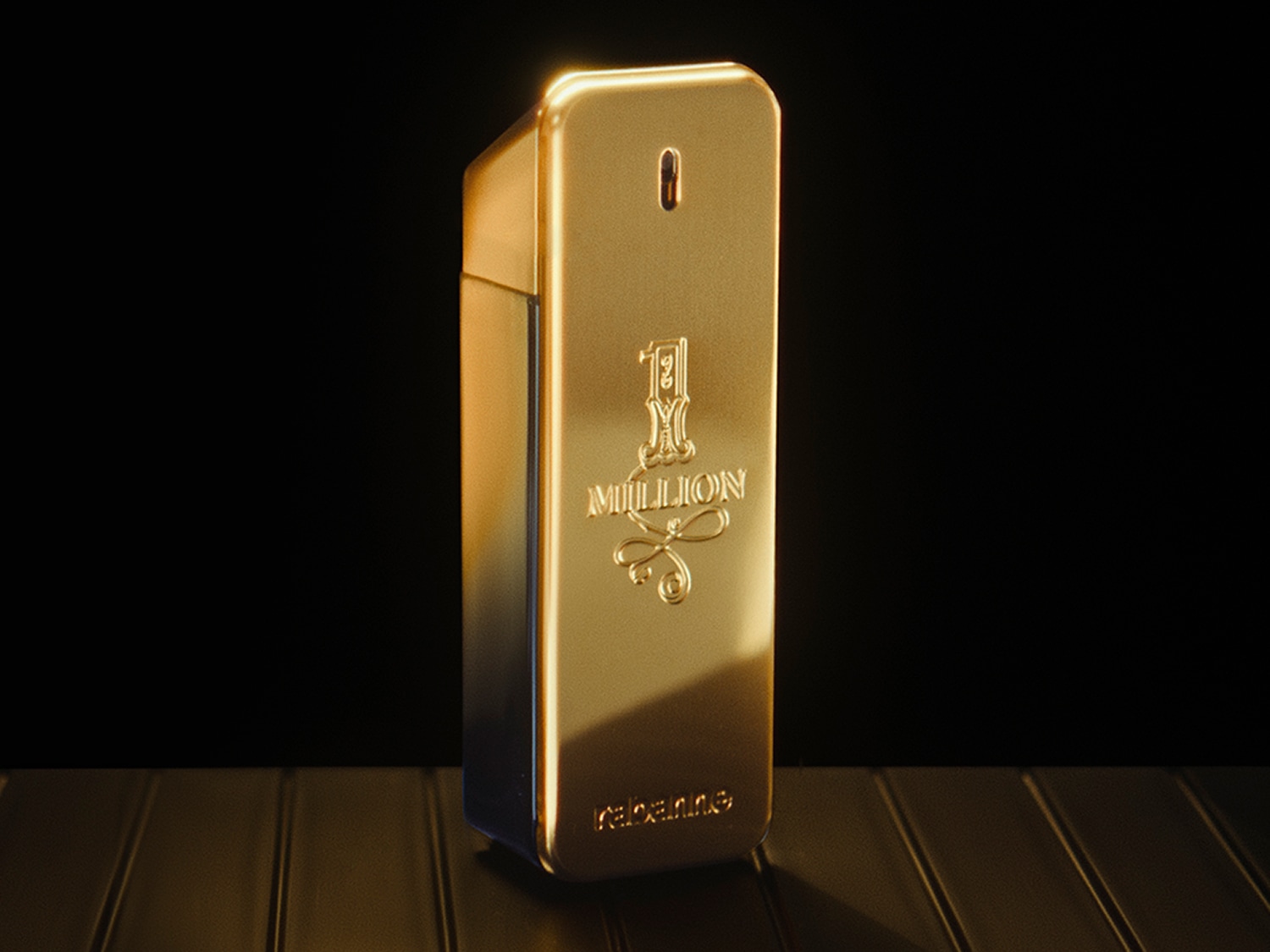 Błyszczący, złoty flakon perfum 1 Million od Paco Rabanne, przypominający sztabkę złota, stoi na metalicznej powierzchni.