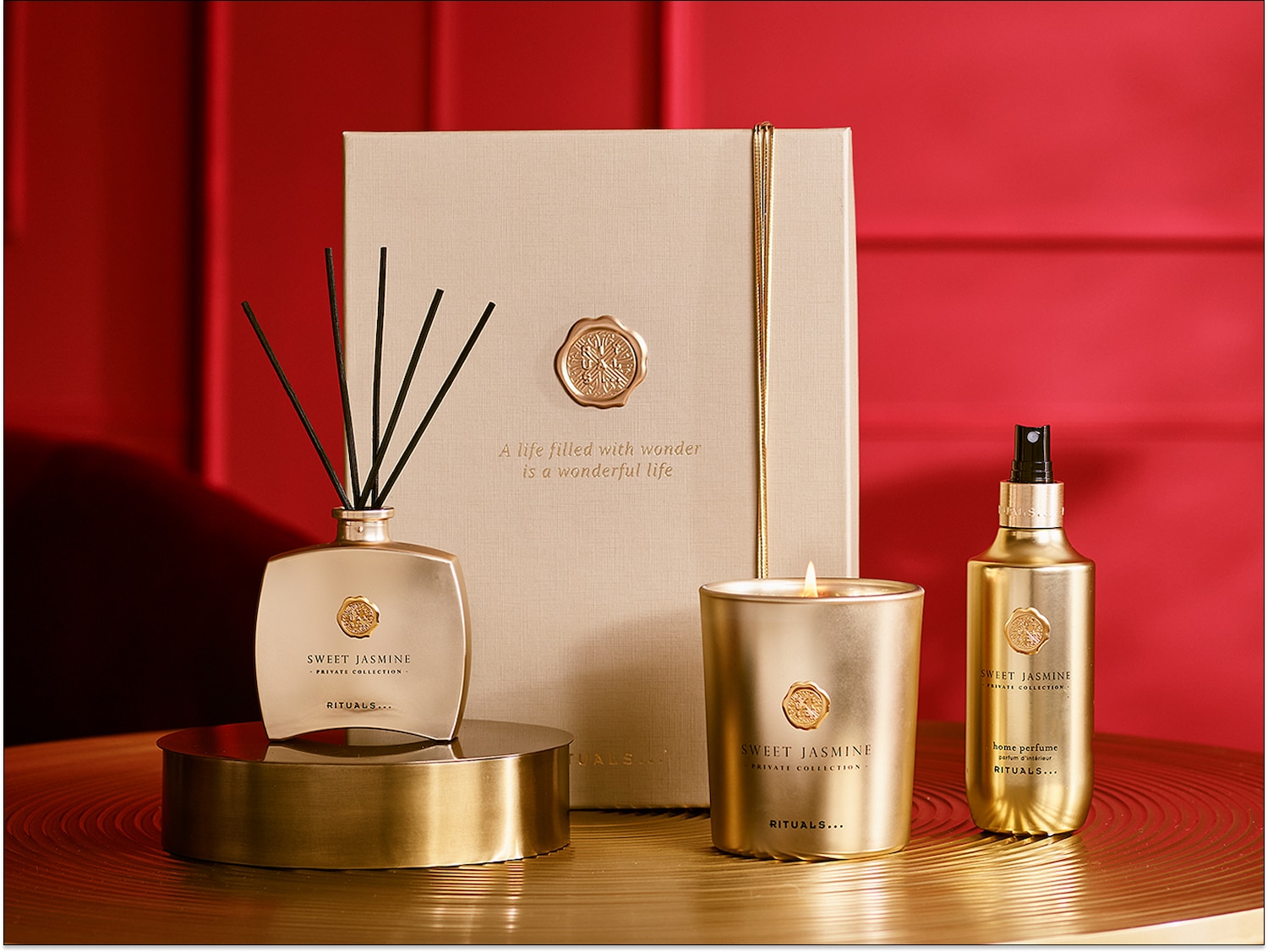 Aromatinis rinkinys iš „Rituals“: auksinės spalvos žvakė, purškiklis ir kvapų difuzorius su lazdelėmis, ant pakuotės užrašas „Sweet Jasmine Private Collection“.