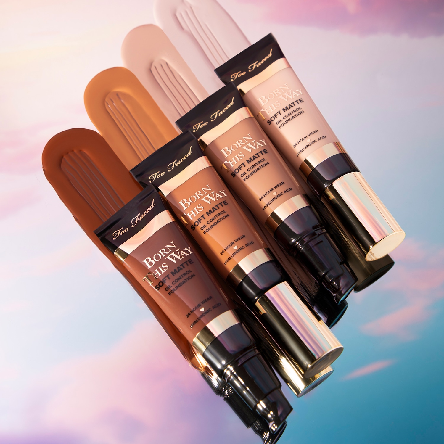 Born This Way Soft Matte Foundation in verschiedenen Farbtönen, die mit jeweiligen Swatches auf einem reflektierenden Untergrund präsentiert werden.