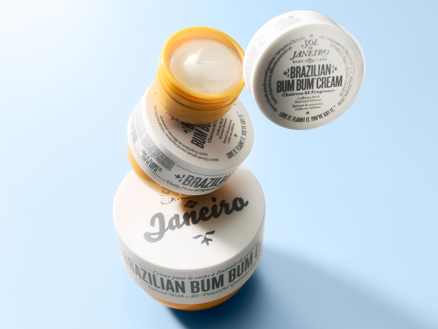 Drie potten Sol de Janeiro Brazilian Bum Bum Cream gestapeld, met de bovenste open om de crèmetextuur te laten zien.