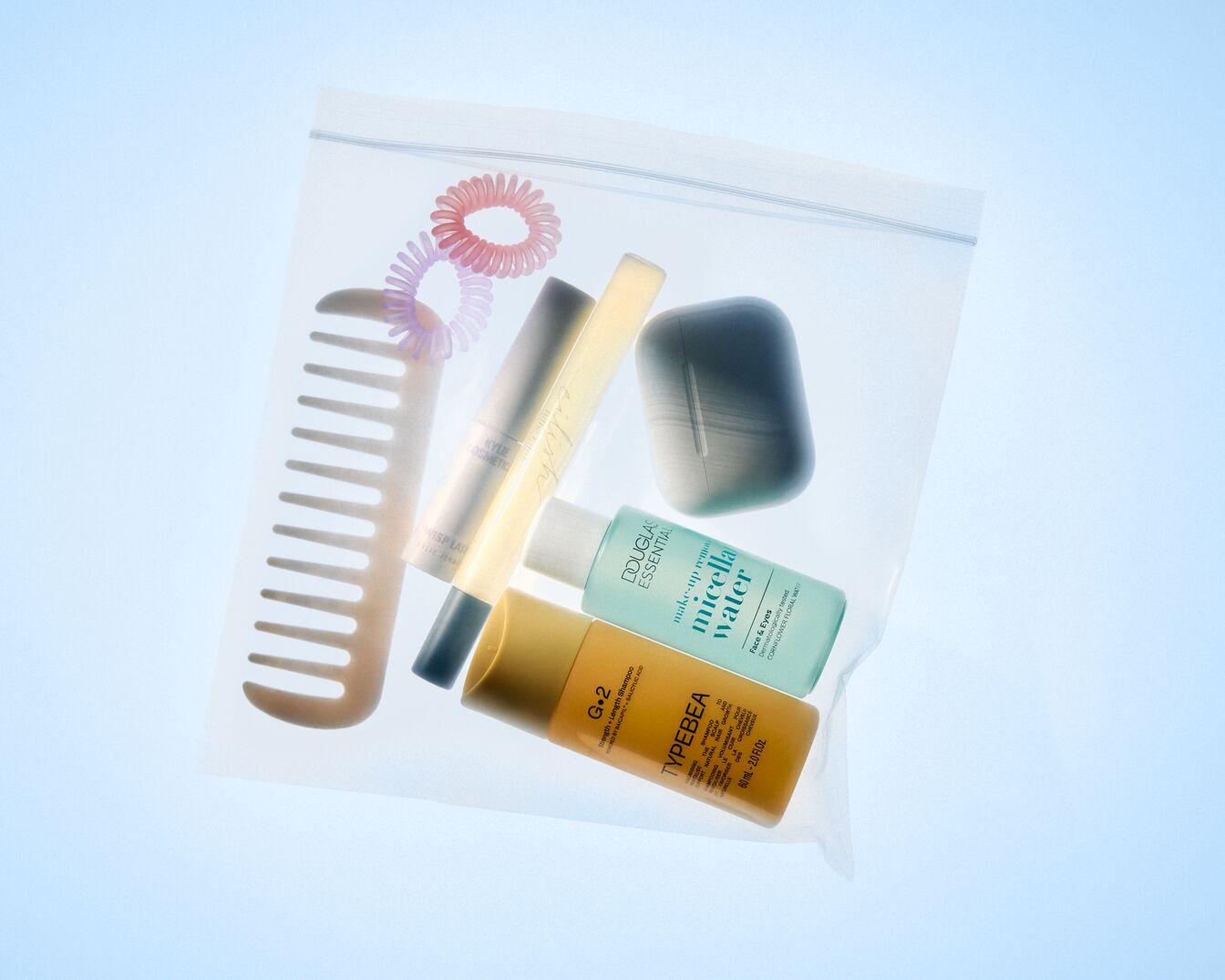 In een transparante zak zitten een kam, haarspelden, Douglas micellair water, TYPEBEA shampoo en een grijze make-up remover.