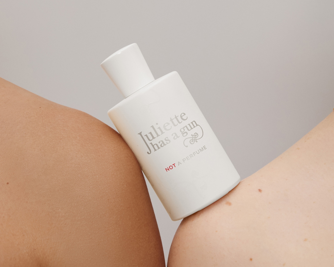 Weiße Flasche „Juliette has a gun NOT A PERFUME“ liegt auf der Haut, minimalistisch und elegant.