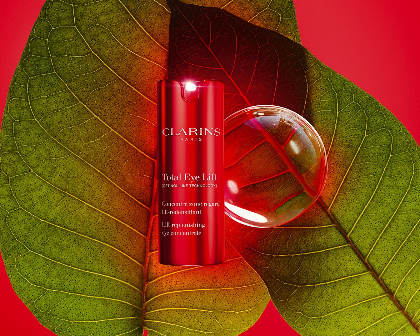Découvrez Total Eye Lift de Clarins, un concentré lift-redensifiant pour le contour des yeux, présenté dans un élégant flacon rouge sur un fond de feuilles vertes et rouges.