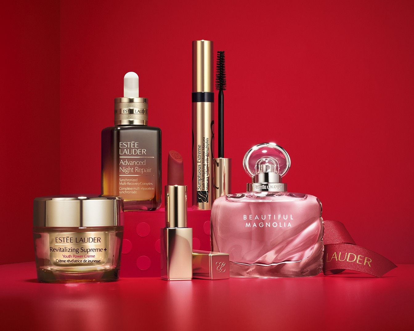 Découvrez un assortiment de produits Estée Lauder, comprenant le sérum Advanced Night Repair, le mascara Sumptuous Extreme, le rouge à lèvres, la crème Revitalizing Supreme+ et le parfum Beautiful Magnolia, présentés sur un fond rouge.