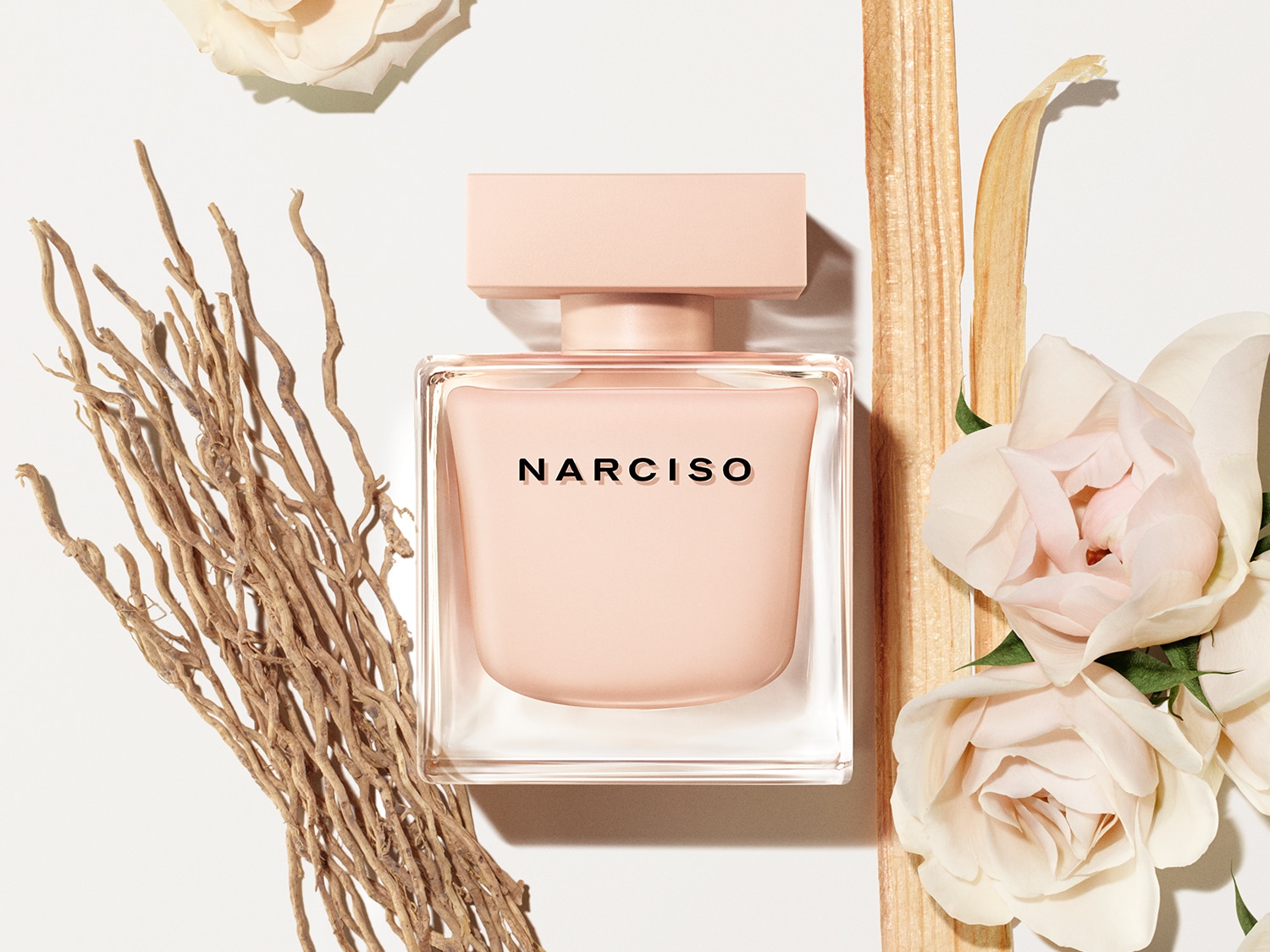 Ein quadratischer, hellrosa Narciso-Parfümflakon steht inmitten von Rosenblüten und hölzernen Akzenten auf einem weißen Hintergrund.