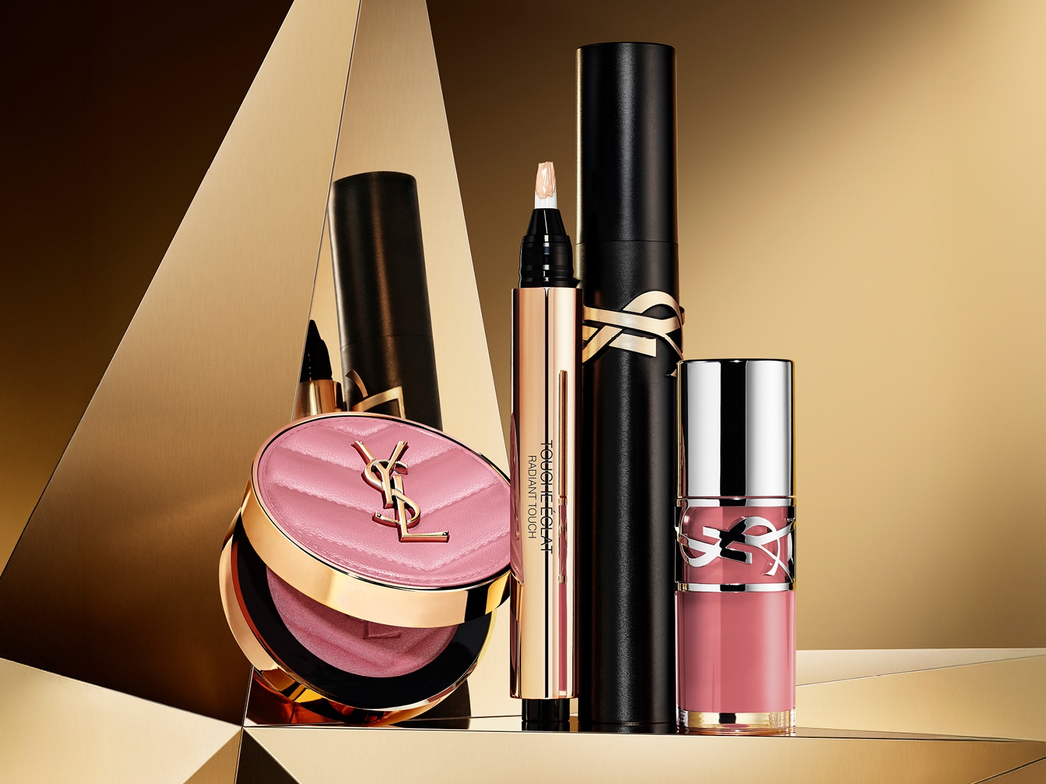 Ontdek de luxe van Yves Saint Laurent met deze collectie: een roze blush in een gouden doosje, een gouden highlighter, zwarte mascara en een roze lipgloss, allemaal tegen een gouden achtergrond.