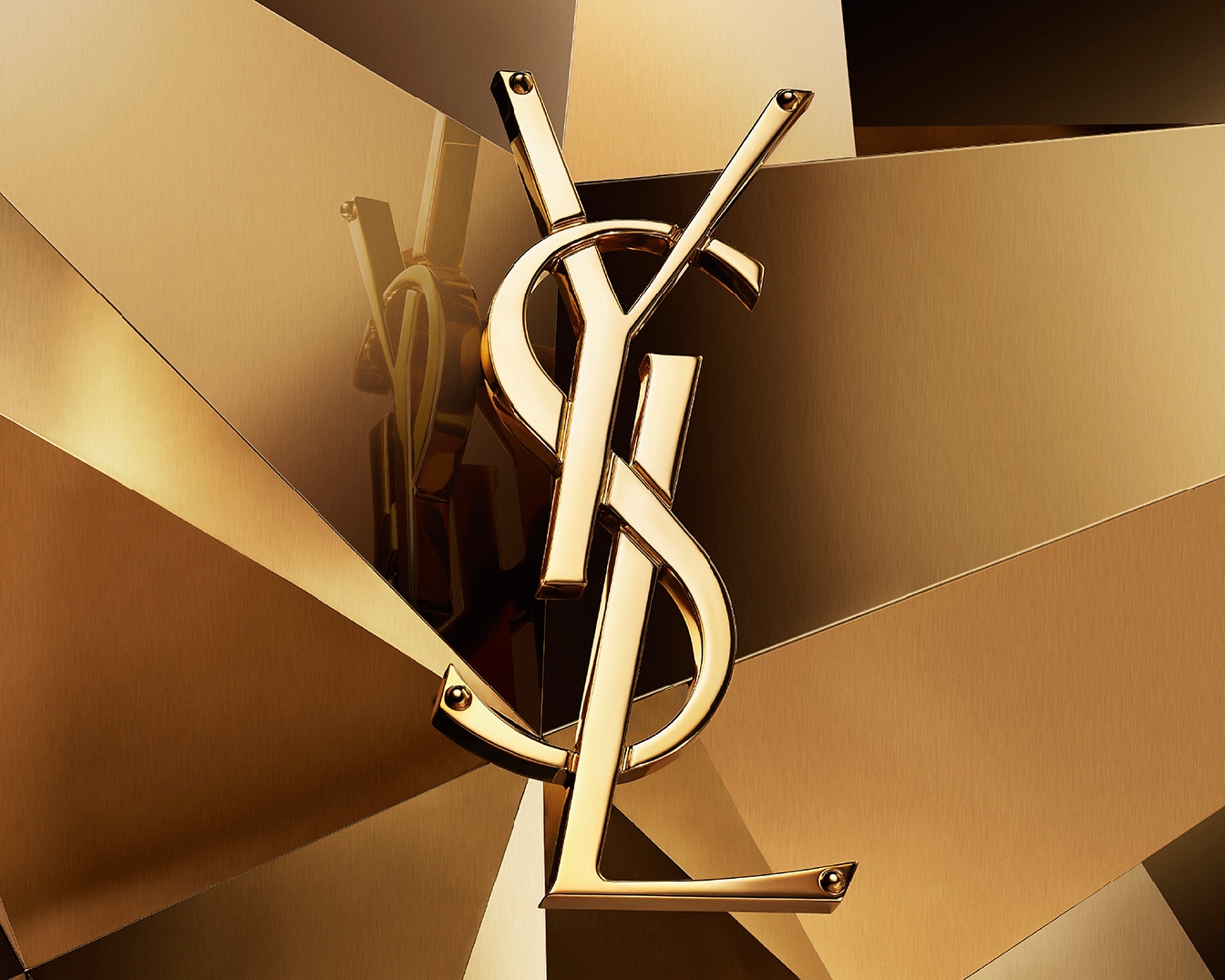 Gouden YSL-logo tegen een achtergrond van gouden geometrische vormen, wat luxe en elegantie uitstraalt.