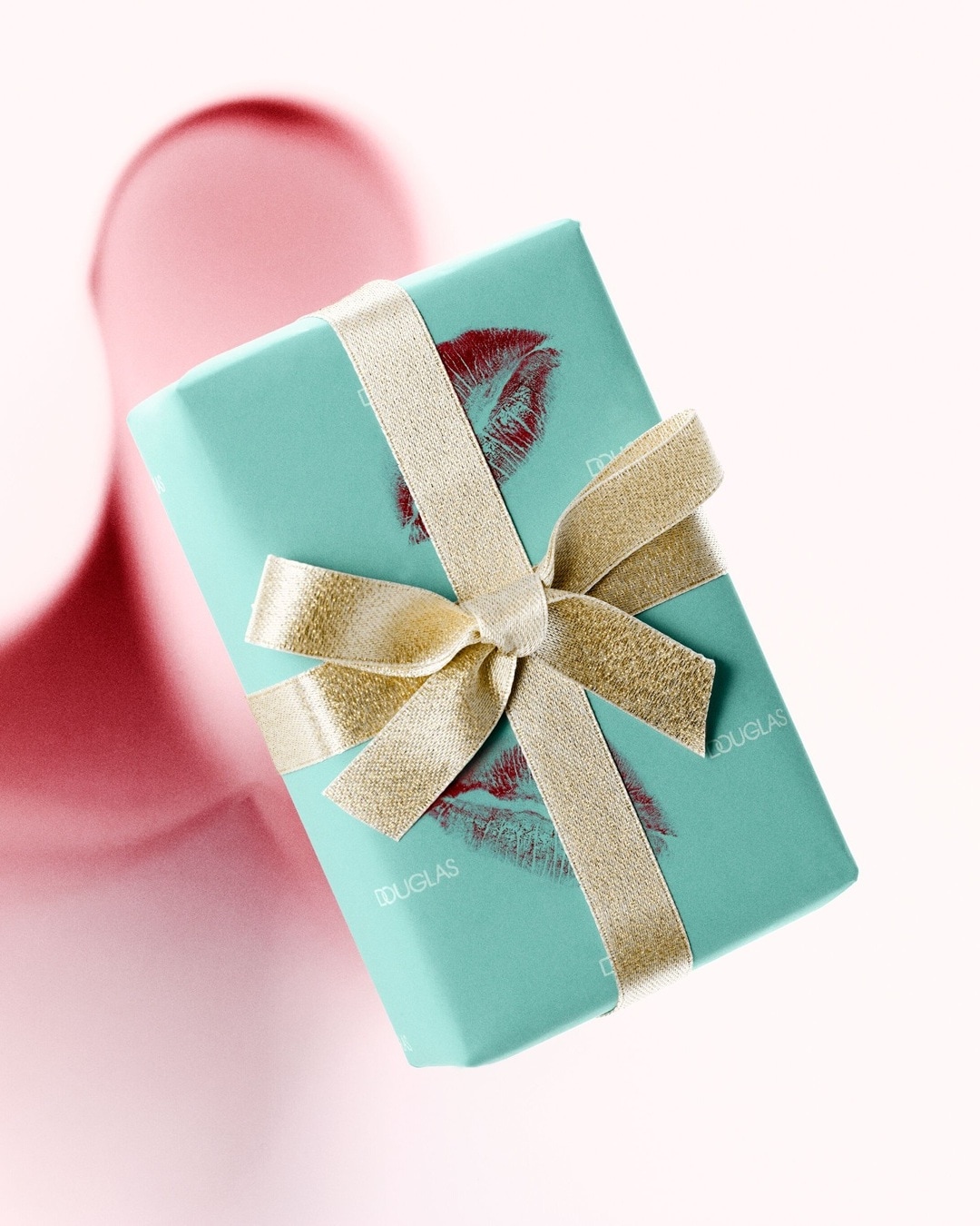 Błękitny prezent od Douglasa, przewiązany złotą wstążką i ozdobiony odciskiem ust, idealny na wyjątkową okazję.