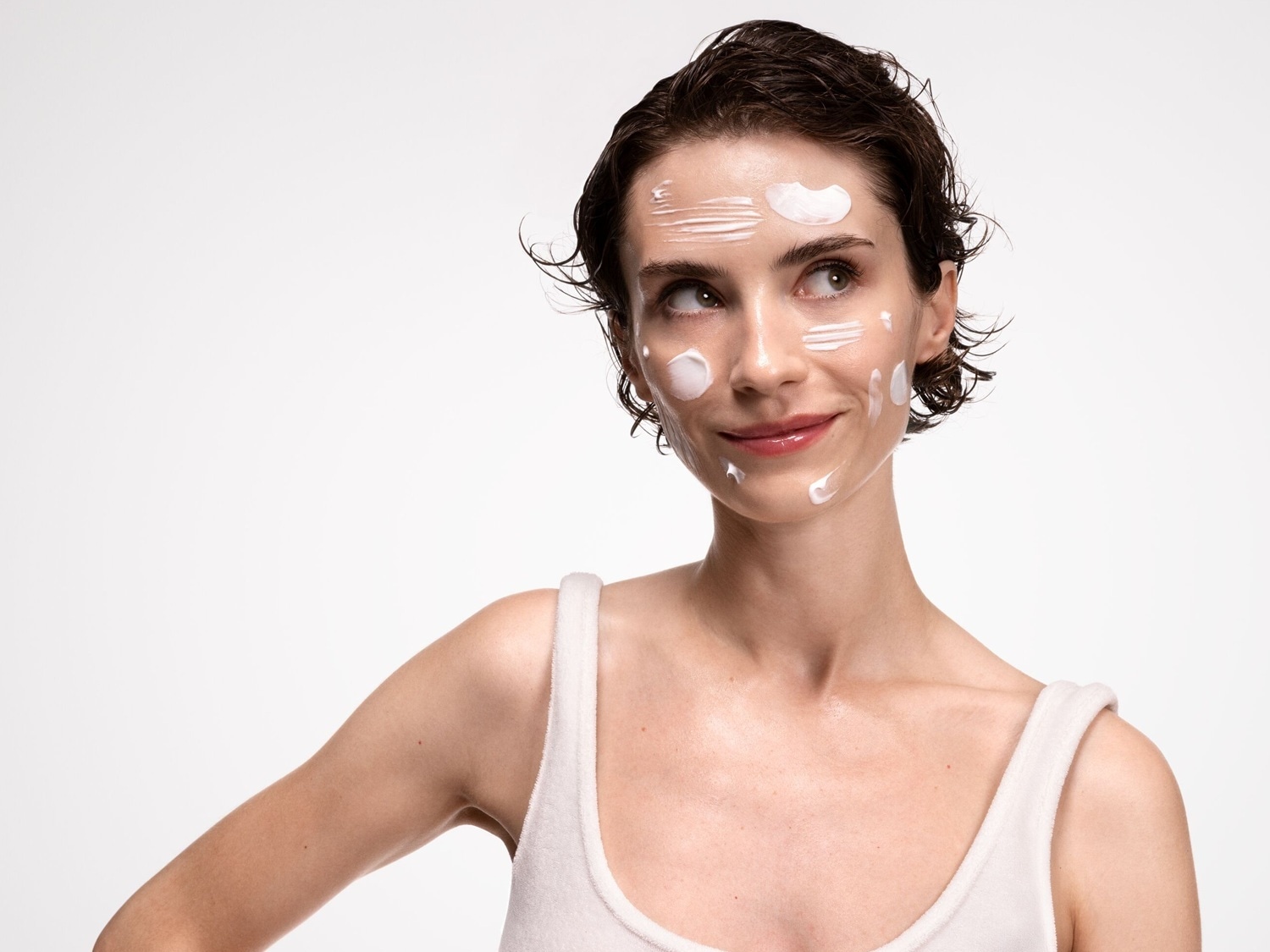 Na twarzy kobiety widać biały krem, który ma nawilżyć i odżywić skórę, nadając jej zdrowy i promienny wygląd.