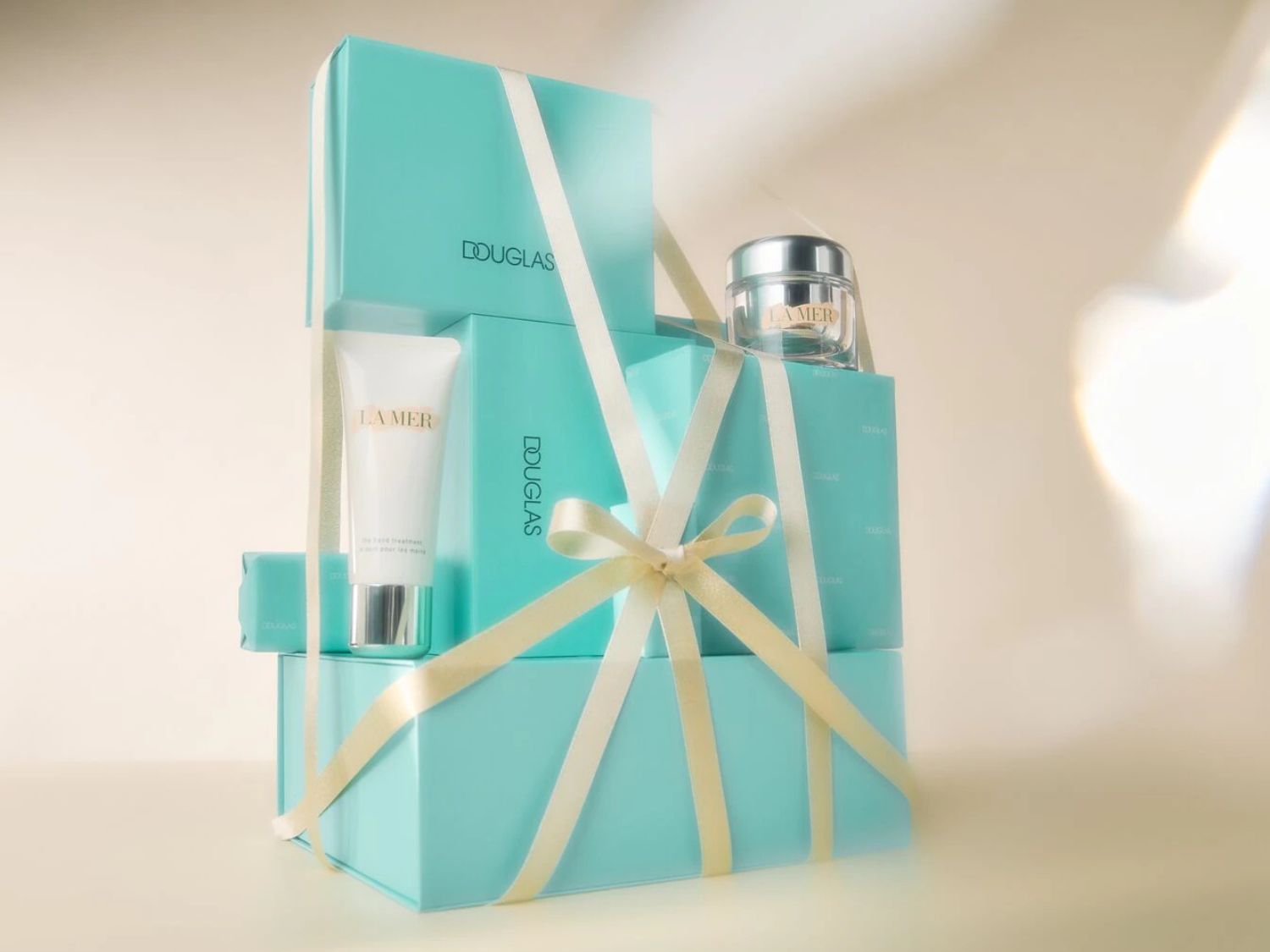 Stapel Douglas geschenkdozen in blauwgroen met La Mer producten, afgewerkt met een crèmekleurig lint.