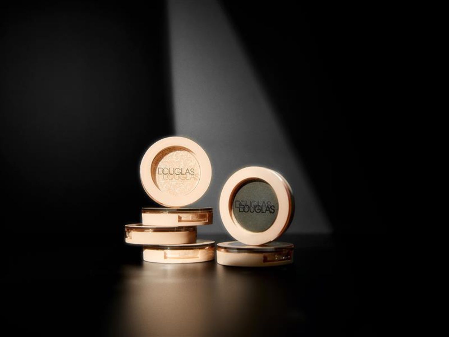 Kompaktné očné tiene Douglas v okrúhlom béžovom obale s logom značky, ktoré sľubujú zvýraznenie vašich očí.