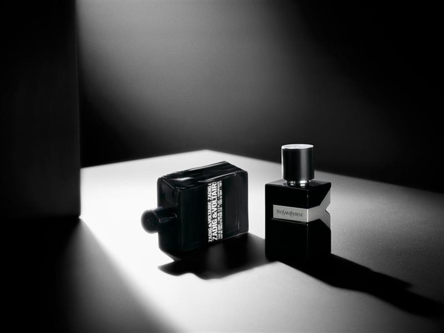 Čierny flakón pánskeho parfumu Yves Saint Laurent s názvom Y leží vedľa flakónu Zadig&Voltaire v čiernom prevedení.