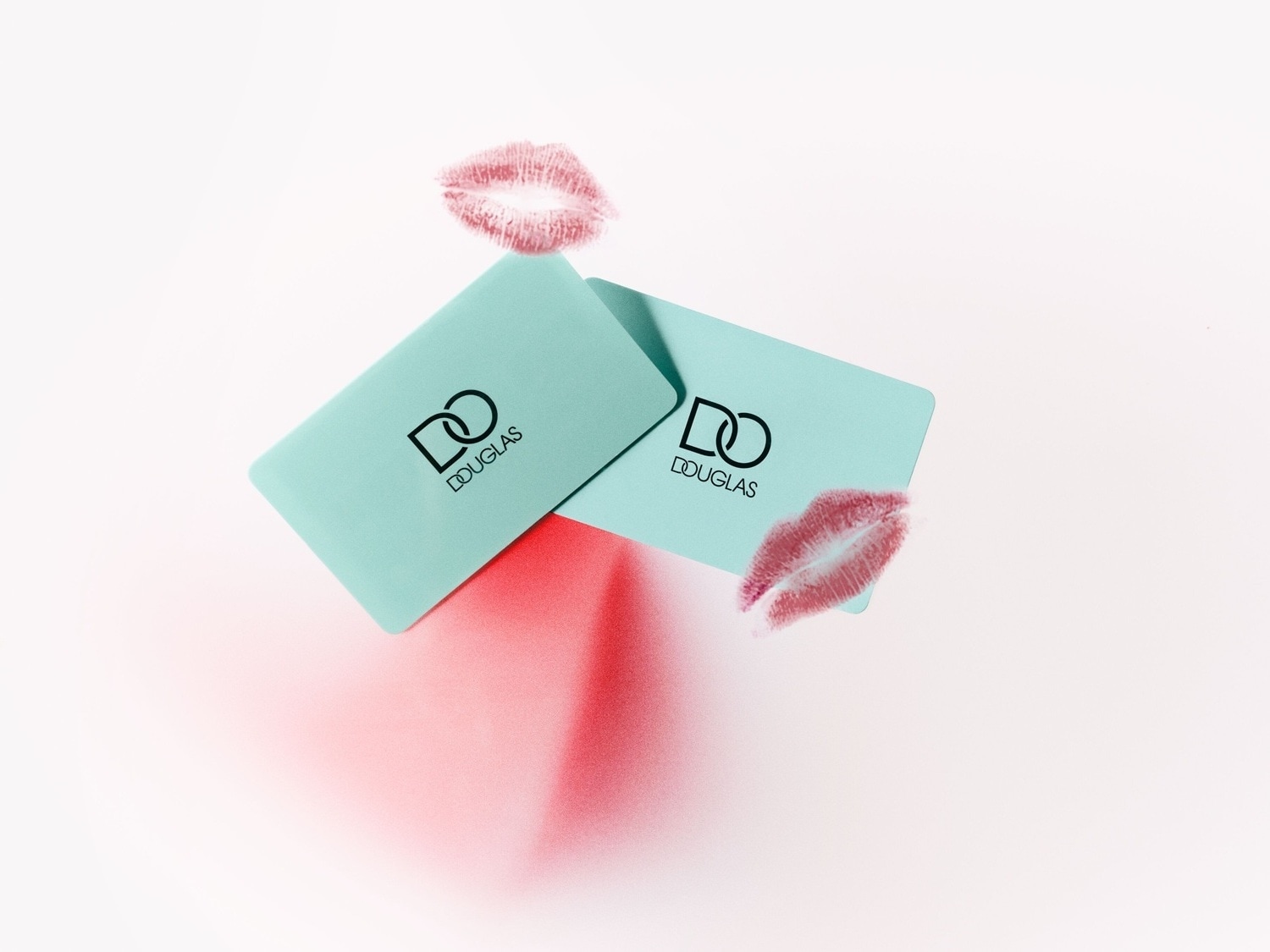 Dwa turkusowe bony upominkowe Douglas leżą na białym tle z odbitymi czerwonymi śladami ust, tworząc elegancką kompozycję.