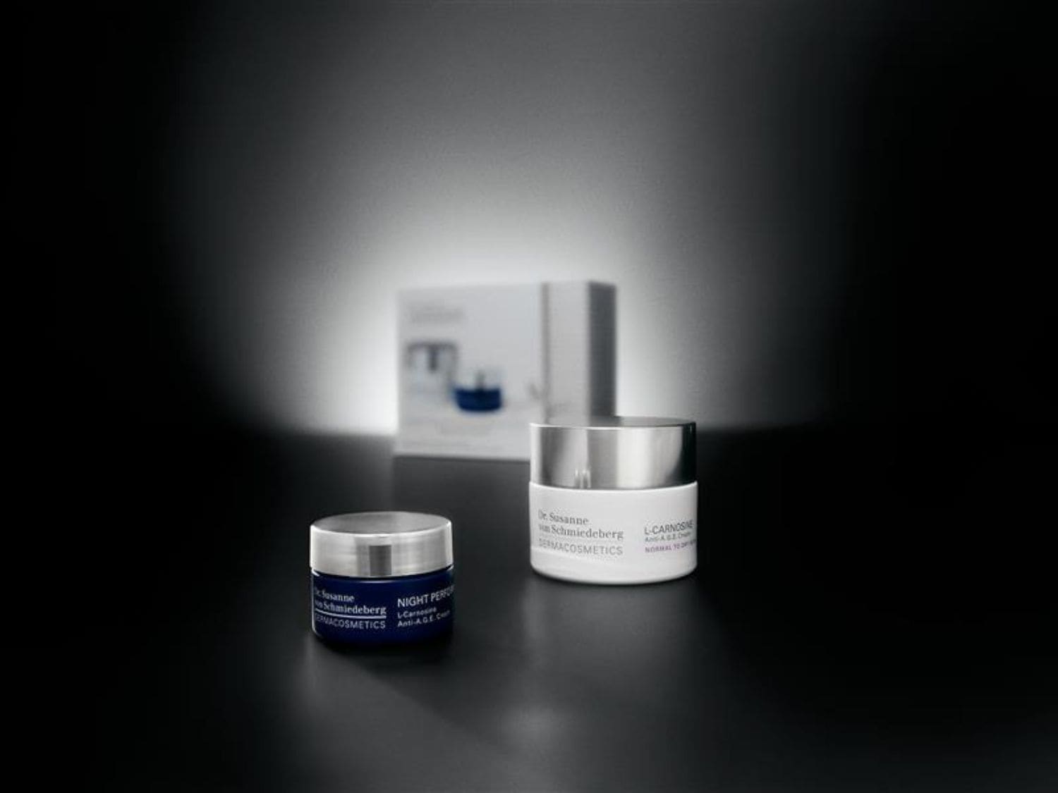 Dr. Susanne Schmiedeberg Derma Cosmetics termékek kék és fehér tégelyben, ezüst színű kupakkal, melyek L-Carnosine Anti-AGE összetevőt tartalmaznak a normál bőrtípusra.