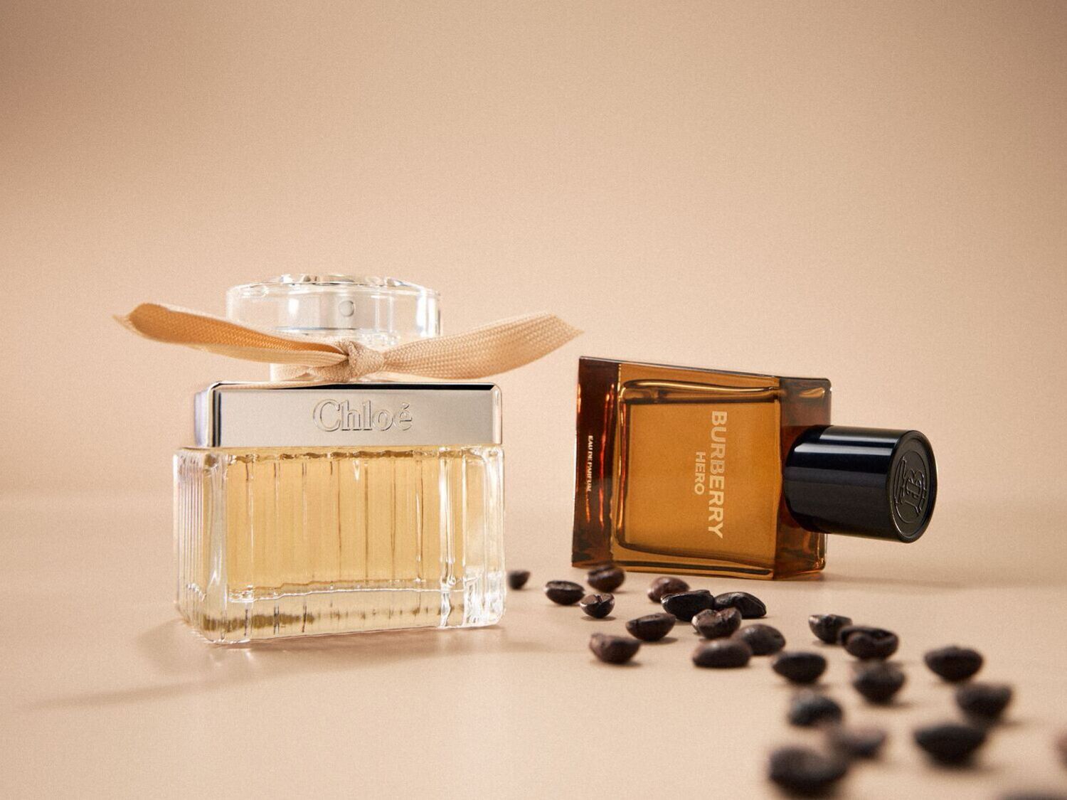 Šalia išdėlioti kavos pupelės, o fone matomi „Chloe“ ir „Burberry Hero“ kvepalų buteliukai, kurių kiekvienas spinduliuoja savitą aromatą.