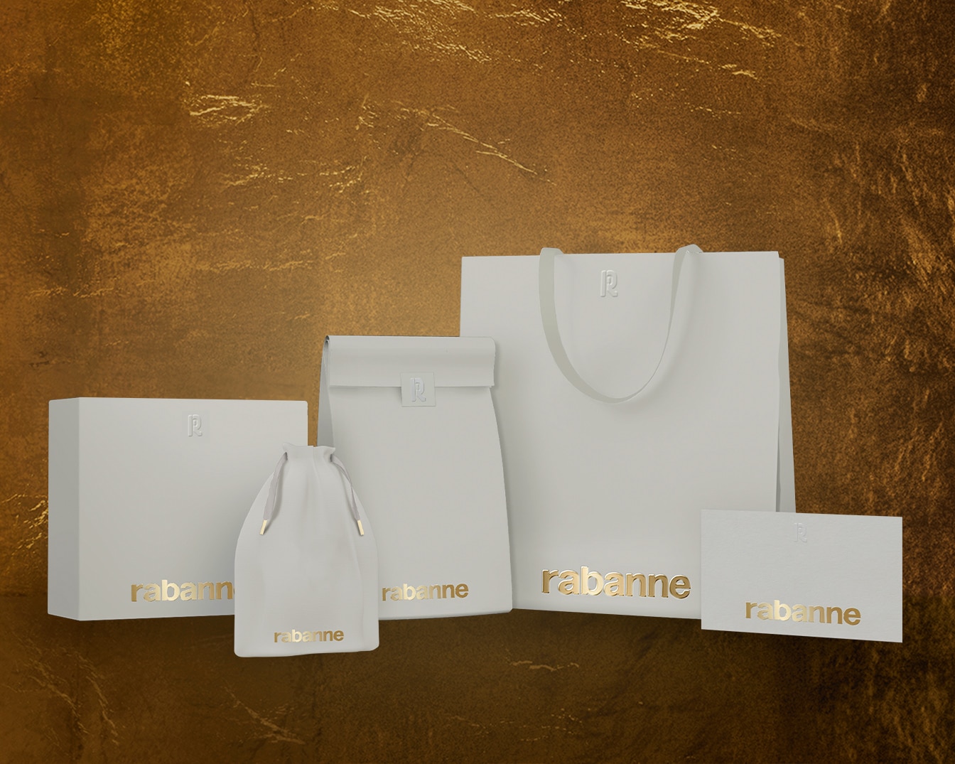 Aquí hay una colección de empaques blancos de Rabanne, que incluyen una caja, una bolsa con cordón, una bolsa de compras y una tarjeta, todos con el logo dorado de Rabanne sobre un fondo dorado texturizado.