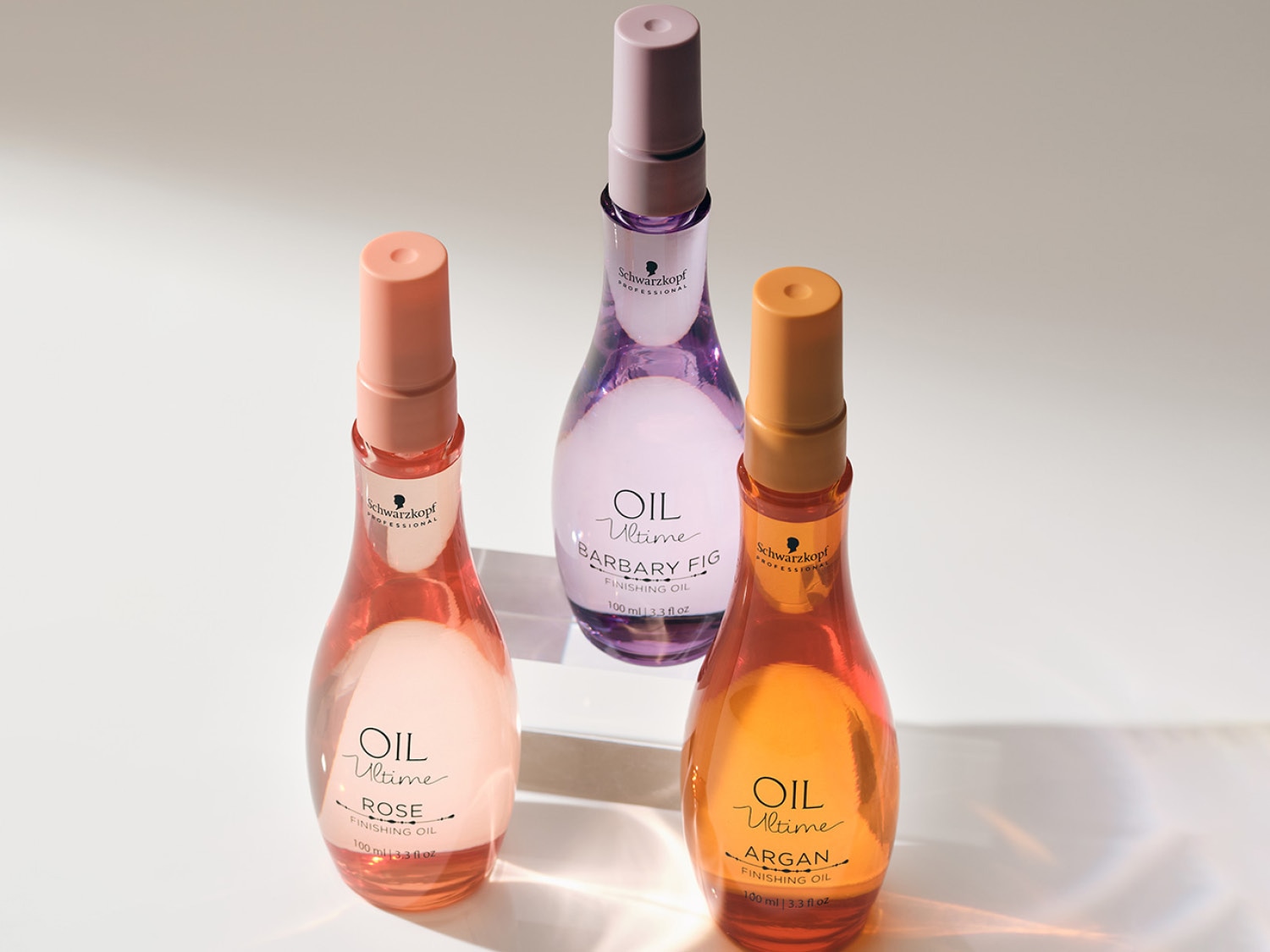 Trzy butelki olejków do włosów Schwarzkopf Oil Ultime: różany, z opuncją figową i arganowy, każdy o pojemności 100 ml, w przezroczystych butelkach z dozownikami w różnych odcieniach.