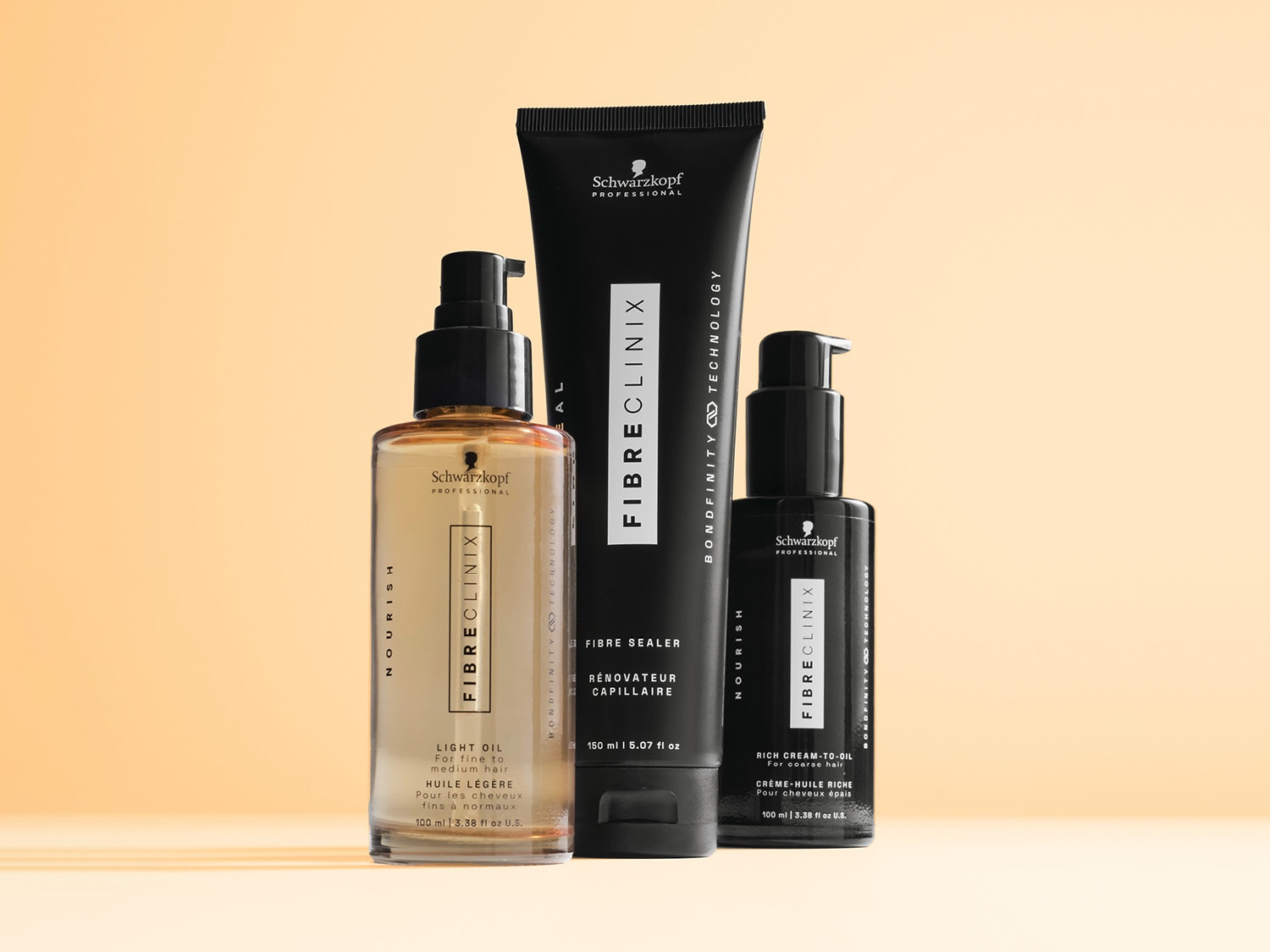 Trzy produkty Schwarzkopf Professional Fibre Clinix Nourish: lekki olejek w przezroczystej butelce, krem do włosów w czarnej tubce i bogaty krem-olejek w czarnej butelce.