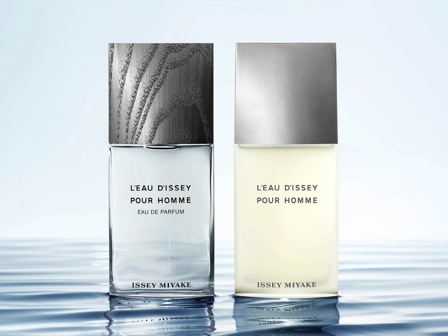 Twee flessen L'EAU D'ISSEY POUR HOMME Eau de Parfum, de ene met een houten dop en de andere met een zilveren dop, staan op een waterige ondergrond.