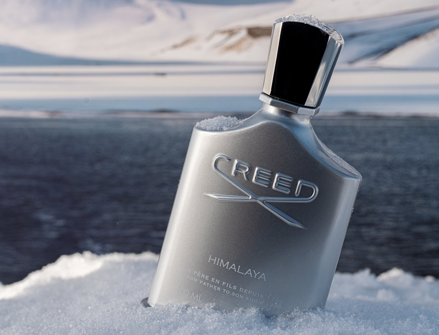 Butelka srebrnych perfum Creed Himalaya o pojemności 100 ml, otoczona śniegiem na tle zimowego krajobrazu, emanuje świeżością i luksusem.