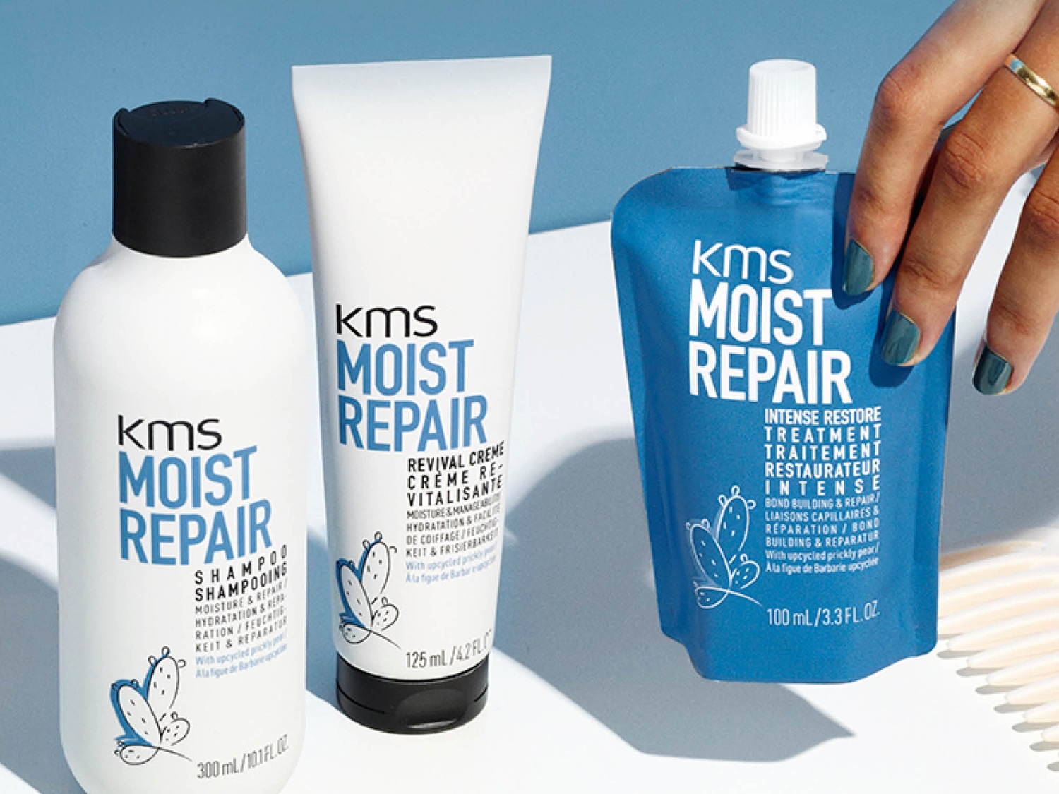 Découvrez le trio KMS Moist Repair : shampooing en flacon blanc, crème revitalisante en tube blanc et soin intense en sachet bleu, pour hydrater et réparer vos cheveux.